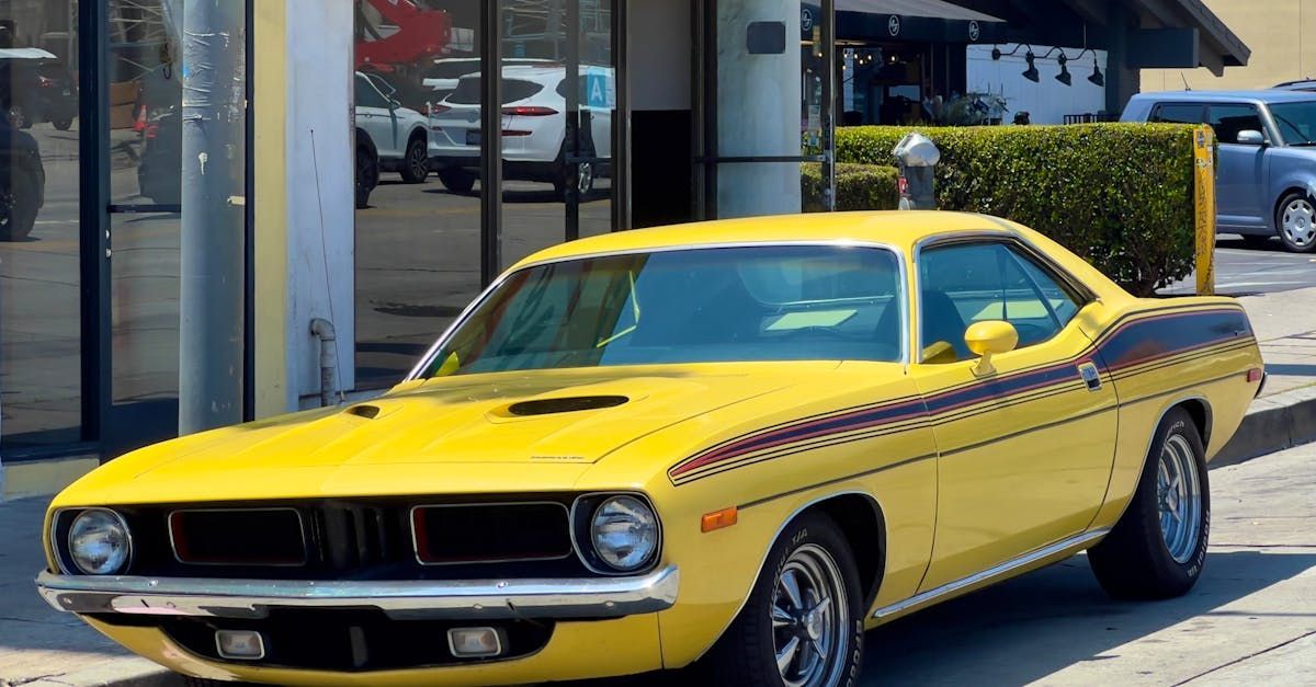 A yellow muscle car is parked in front of a building.