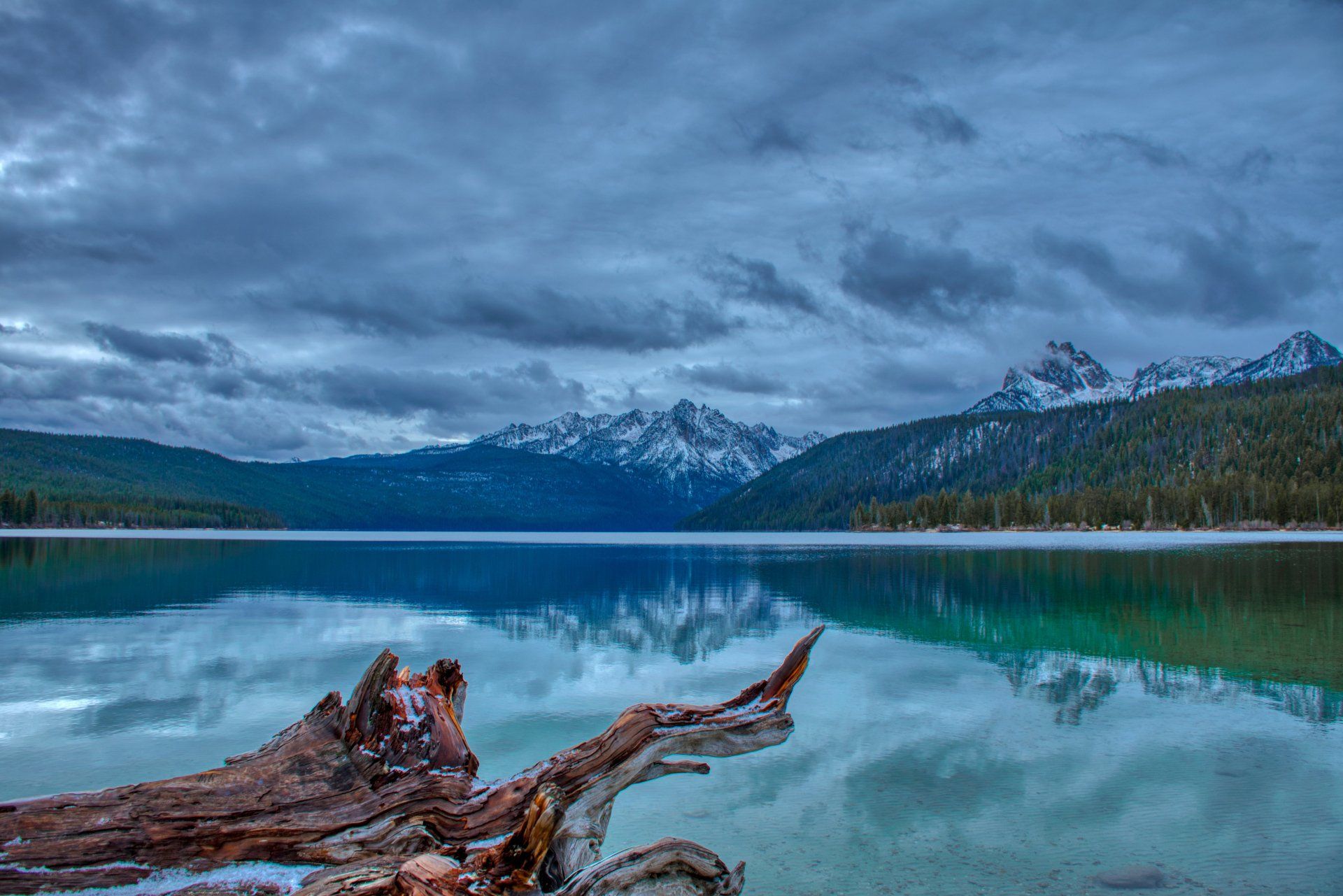 A lake with mountains in the background and a log in the foreground.