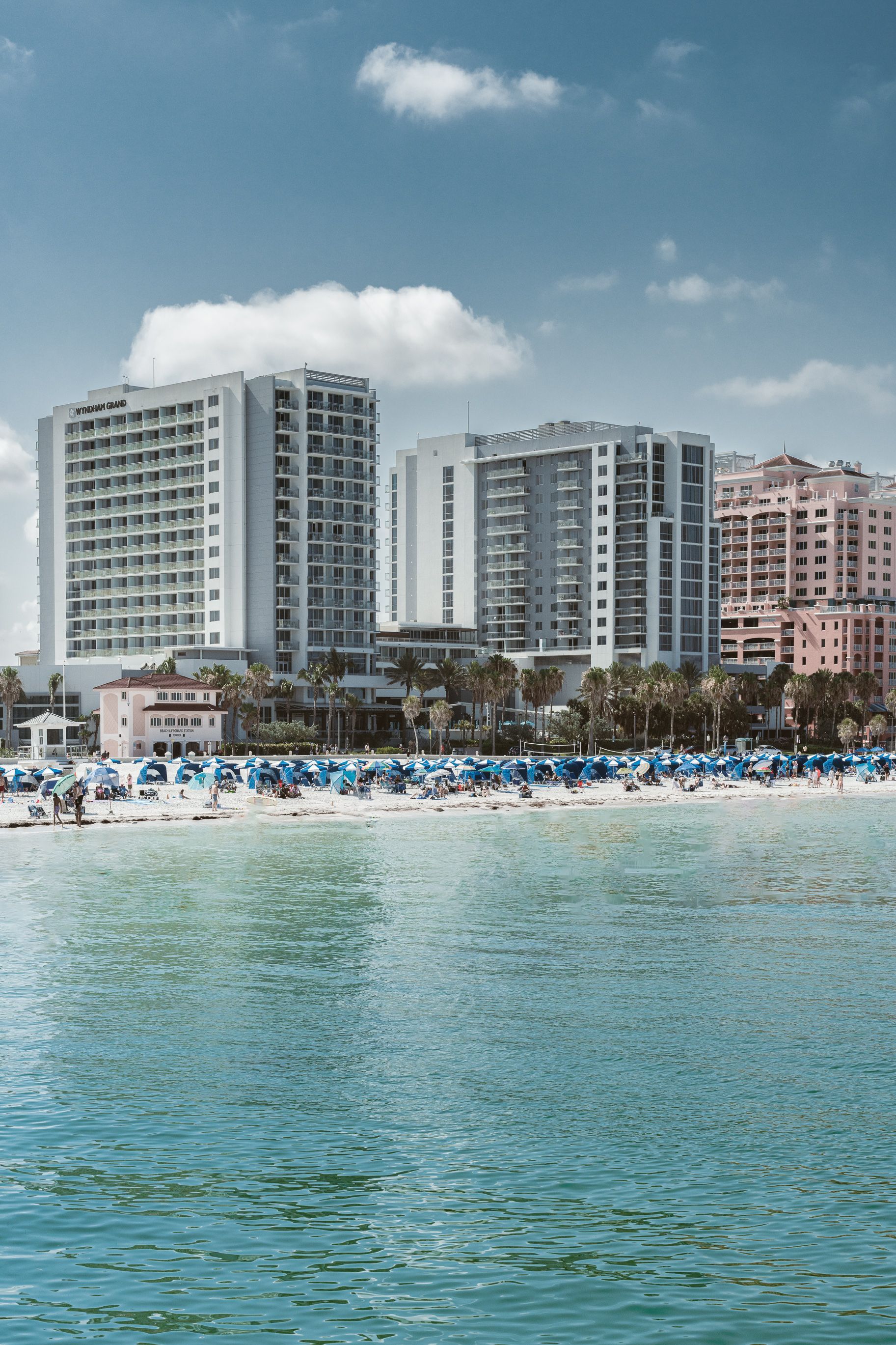 A view of a beach from the water with a city in the background.