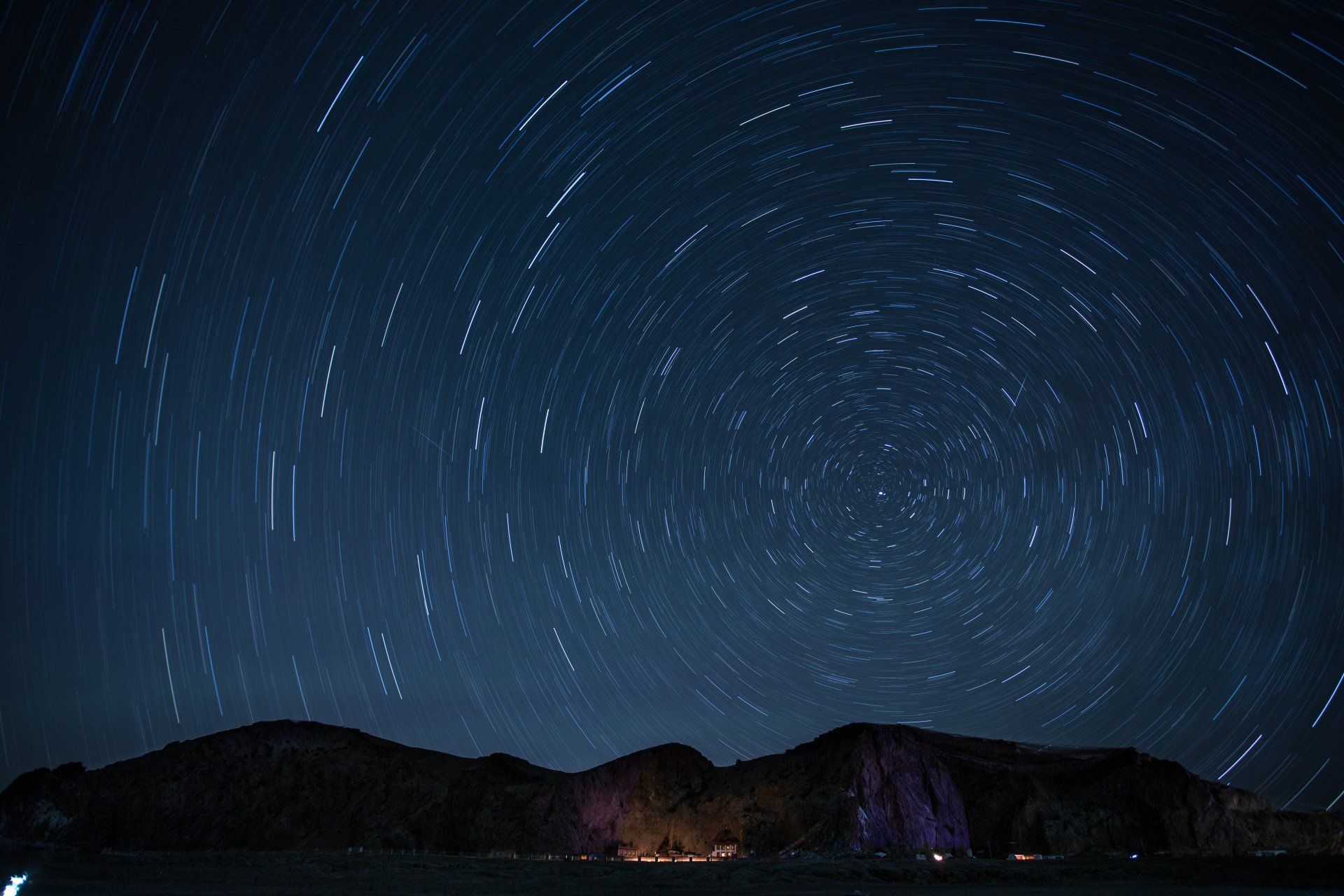 A night sky filled with lots of stars and mountains in the background.