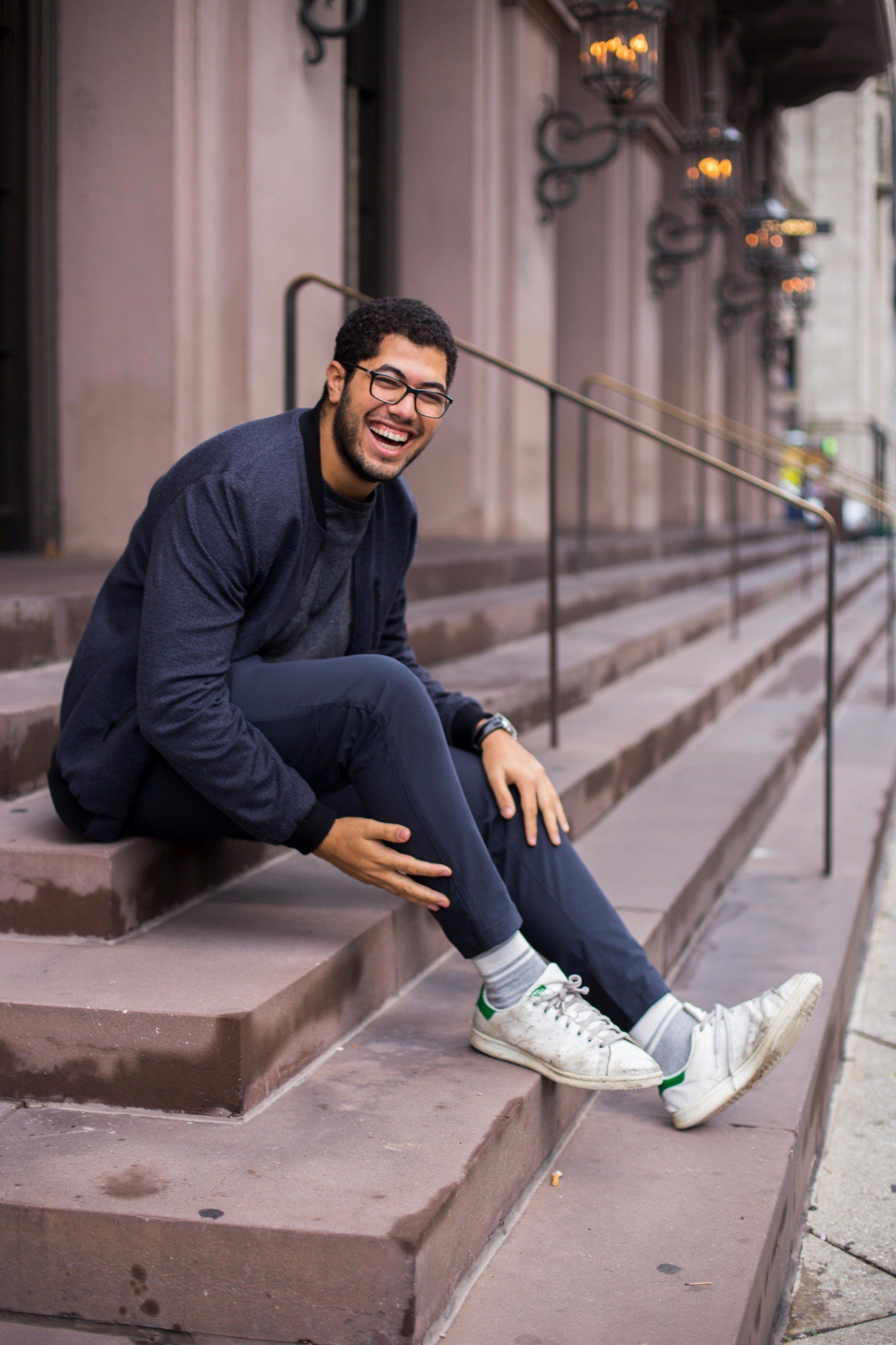 A man is sitting on a set of stairs and smiling.