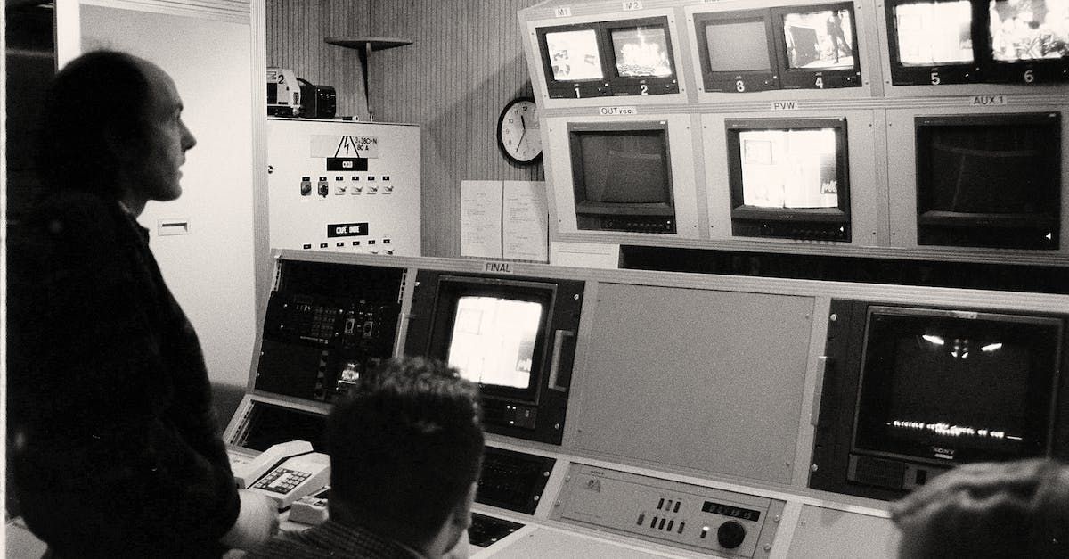 People in a vintage television control room, monitoring screens.
