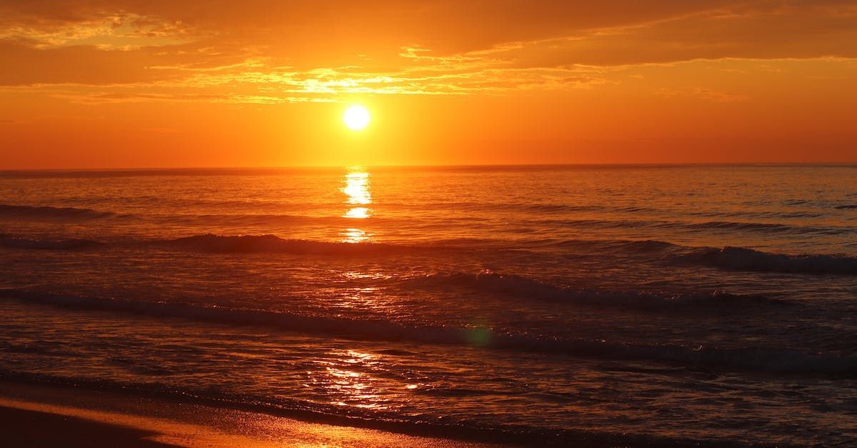 Sunrise over ocean county beach with golden sunlight reflecting on water.