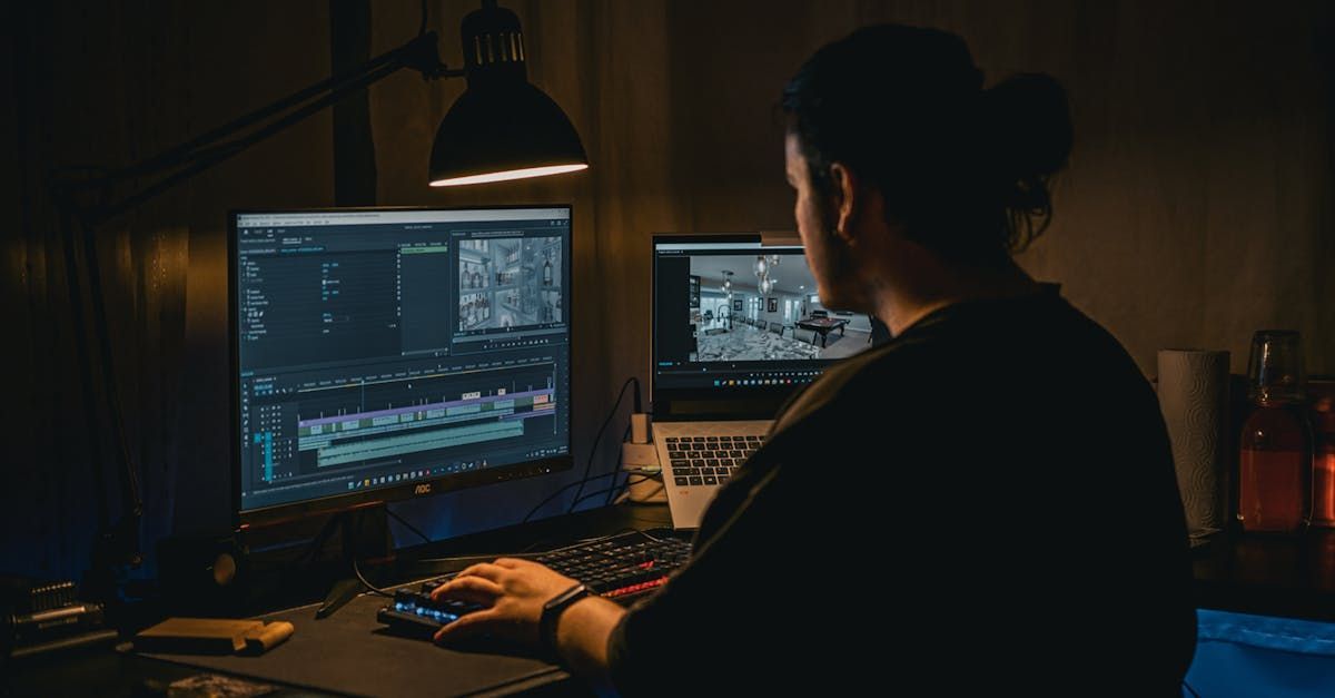 A man is sitting in front of a computer in a dark room.