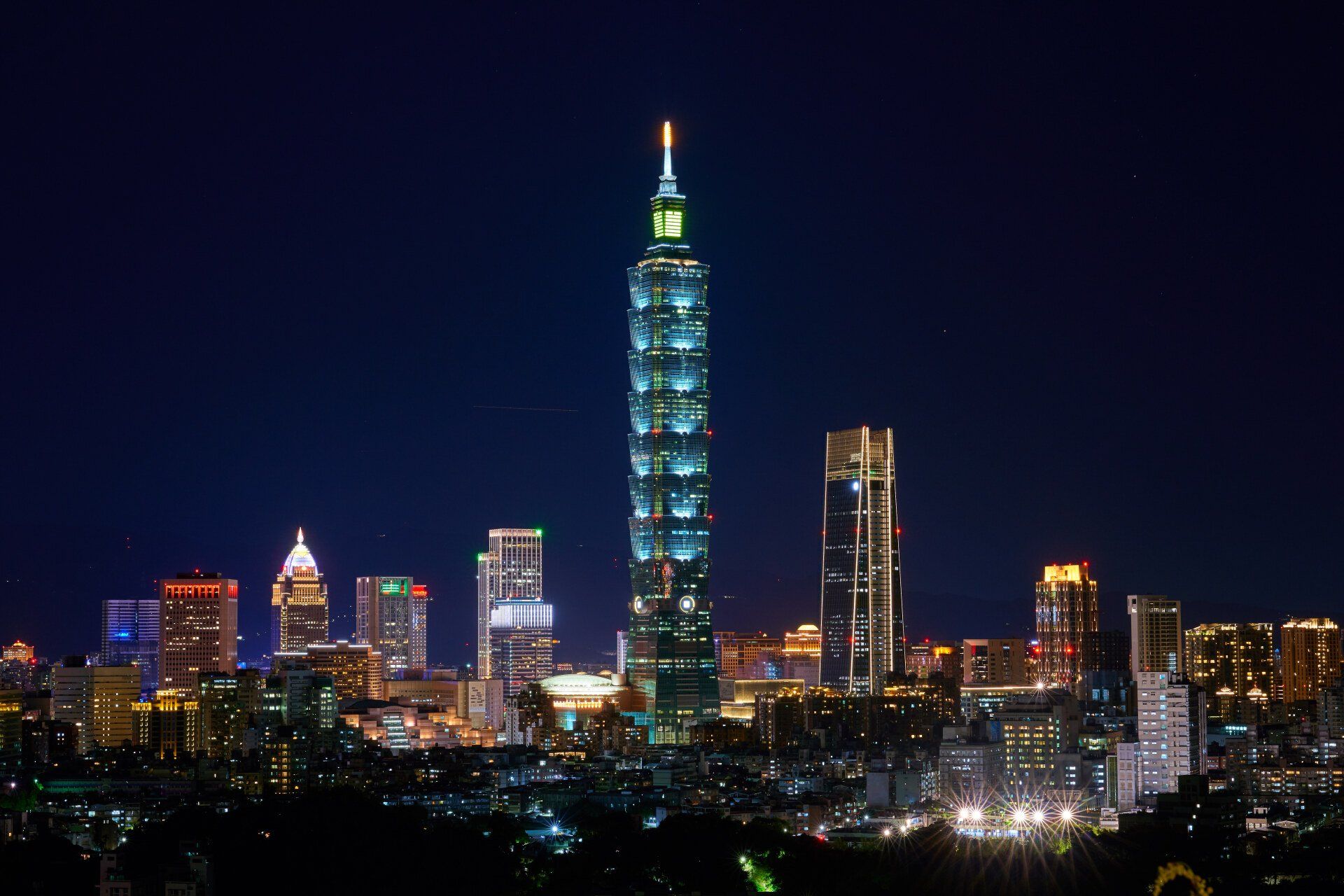 Taipeis skyline om natten, med Taipei 101 oplyst mod en mørkeblå himmel.