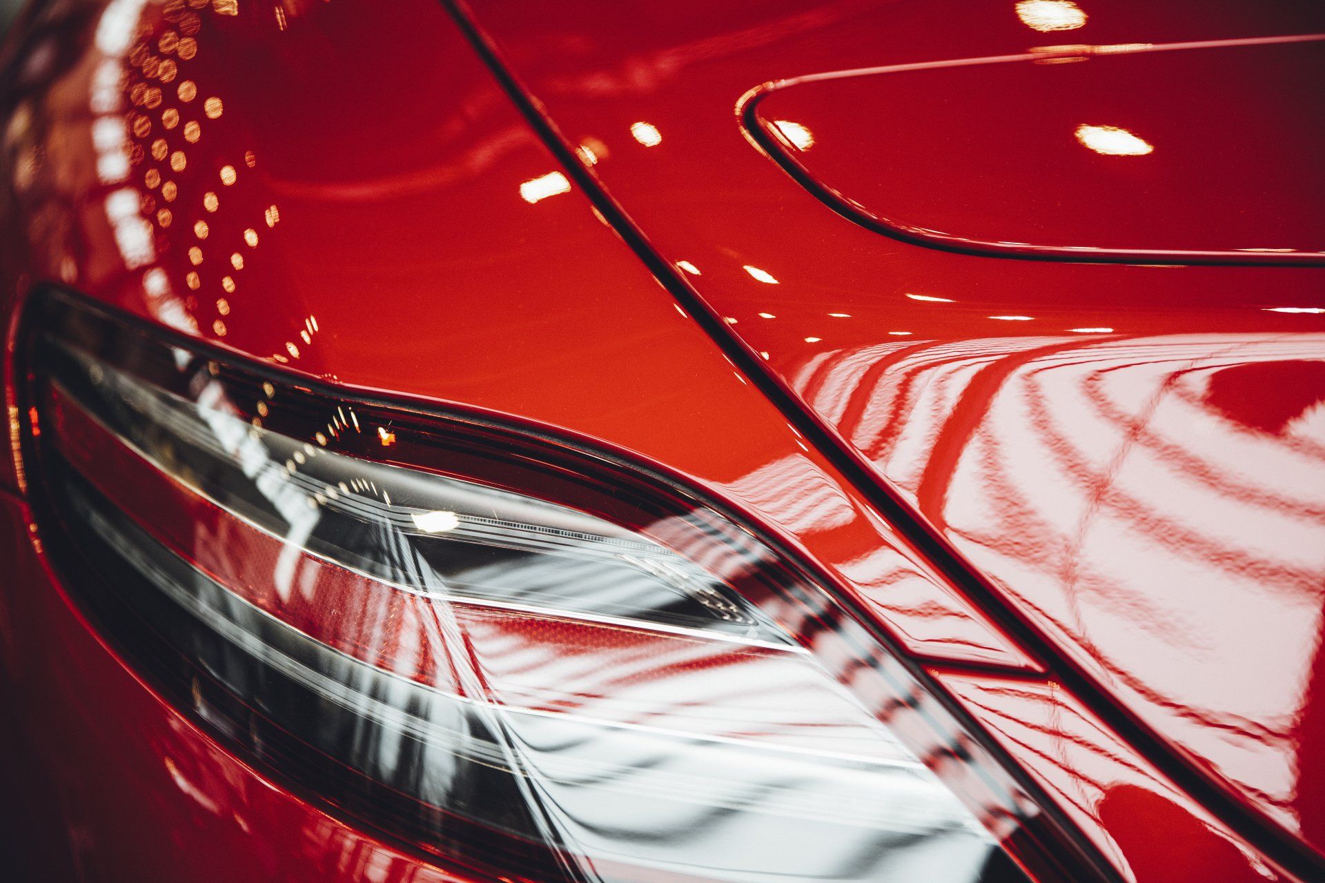 A close up of a red car 's headlight in a showroom.