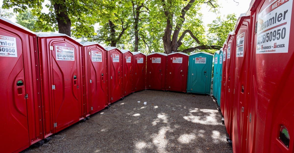 a green dumpster and a green portable toilet are parked next to each other .