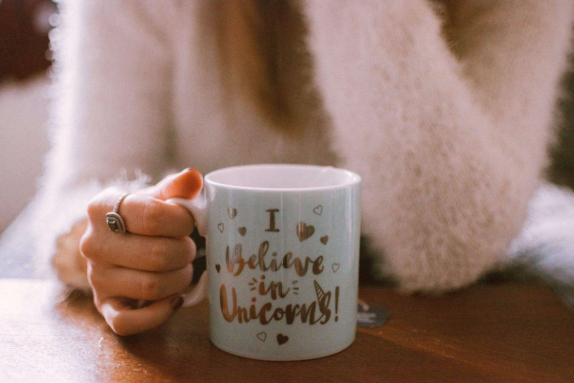 Une femme tient une tasse qui dit « je crois aux licornes ».