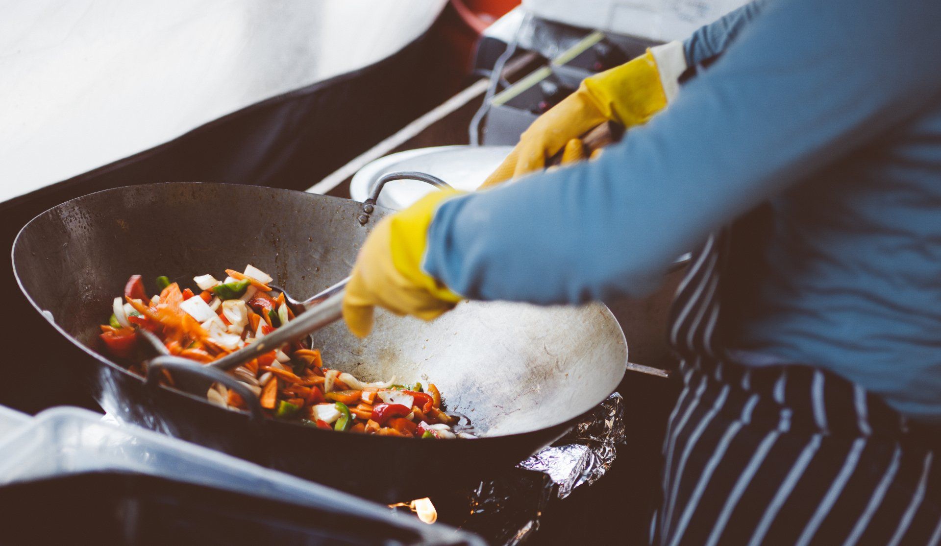 a person is cooking food in a wok on a stove .