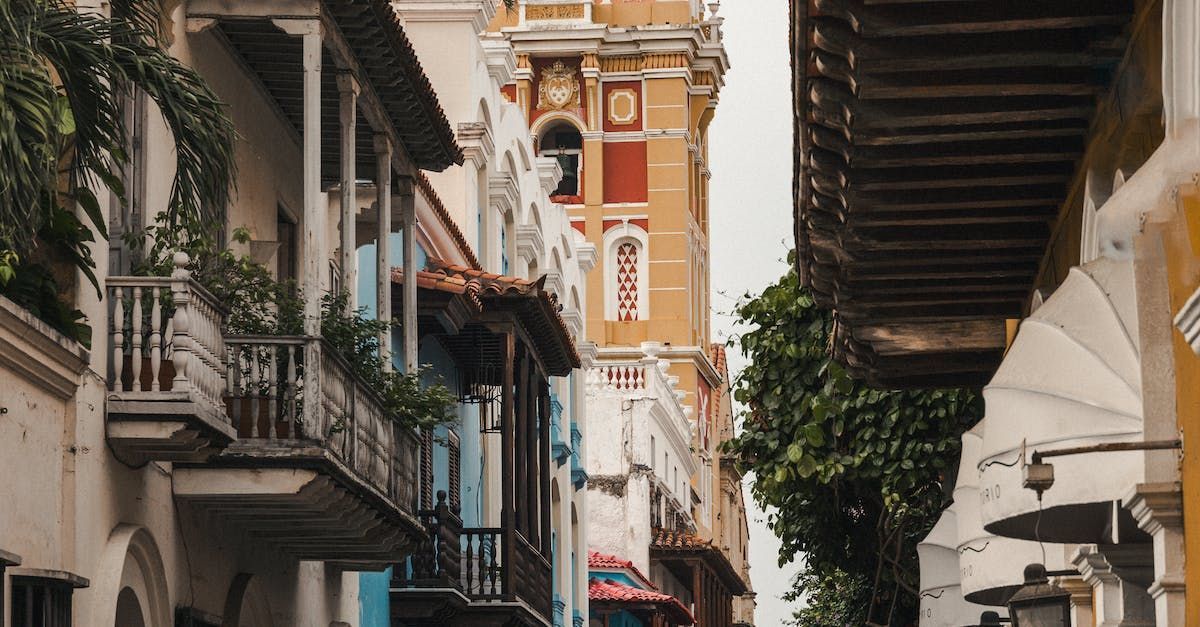 Una calle estrecha en una ciudad con una torre de reloj al fondo.