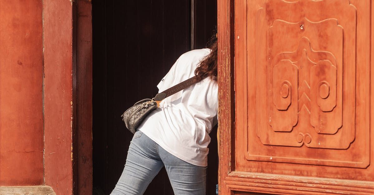 A woman is standing in a doorway holding a purse.