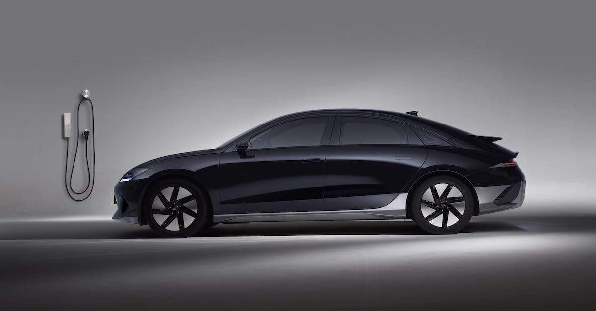 A black electric car is being charged at a charging station.