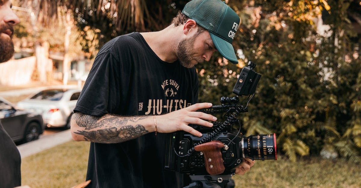 A man is holding a camera and talking to another man.