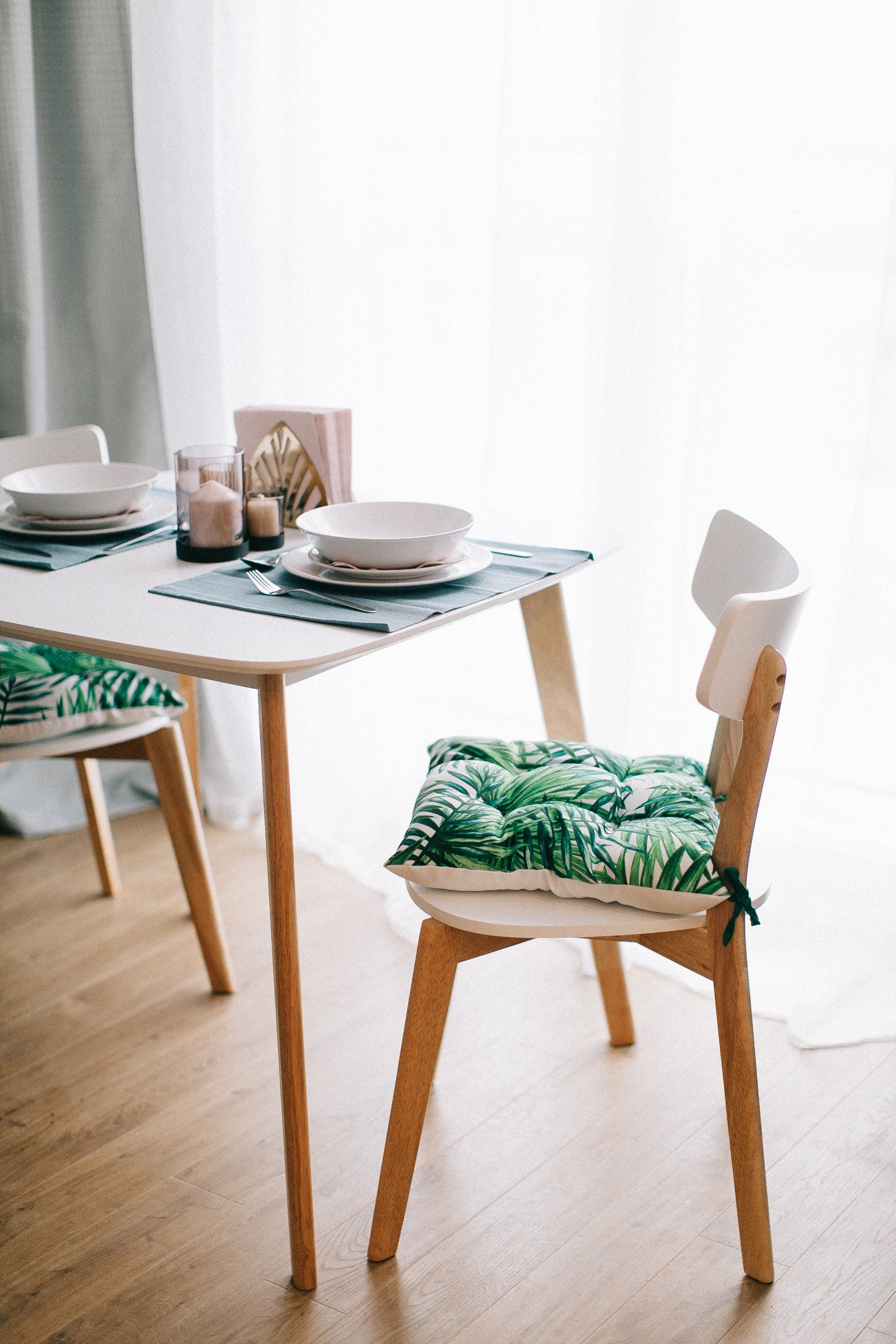 A dining room with a table and chairs and plates on it.