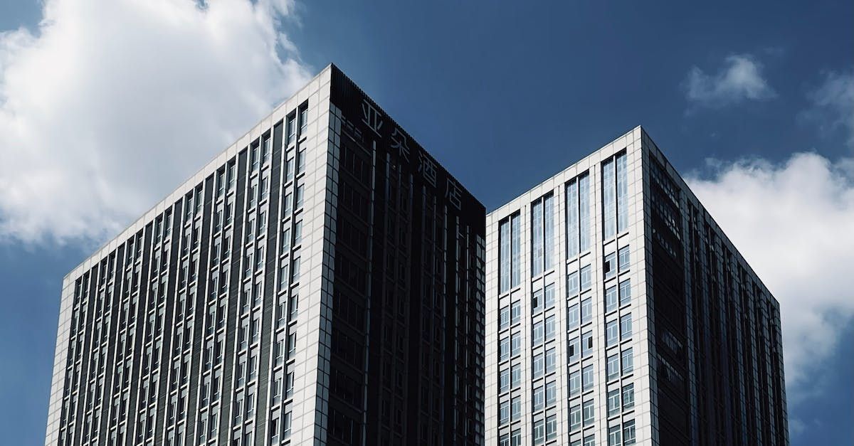 two tall buildings are against a blue sky with clouds .
