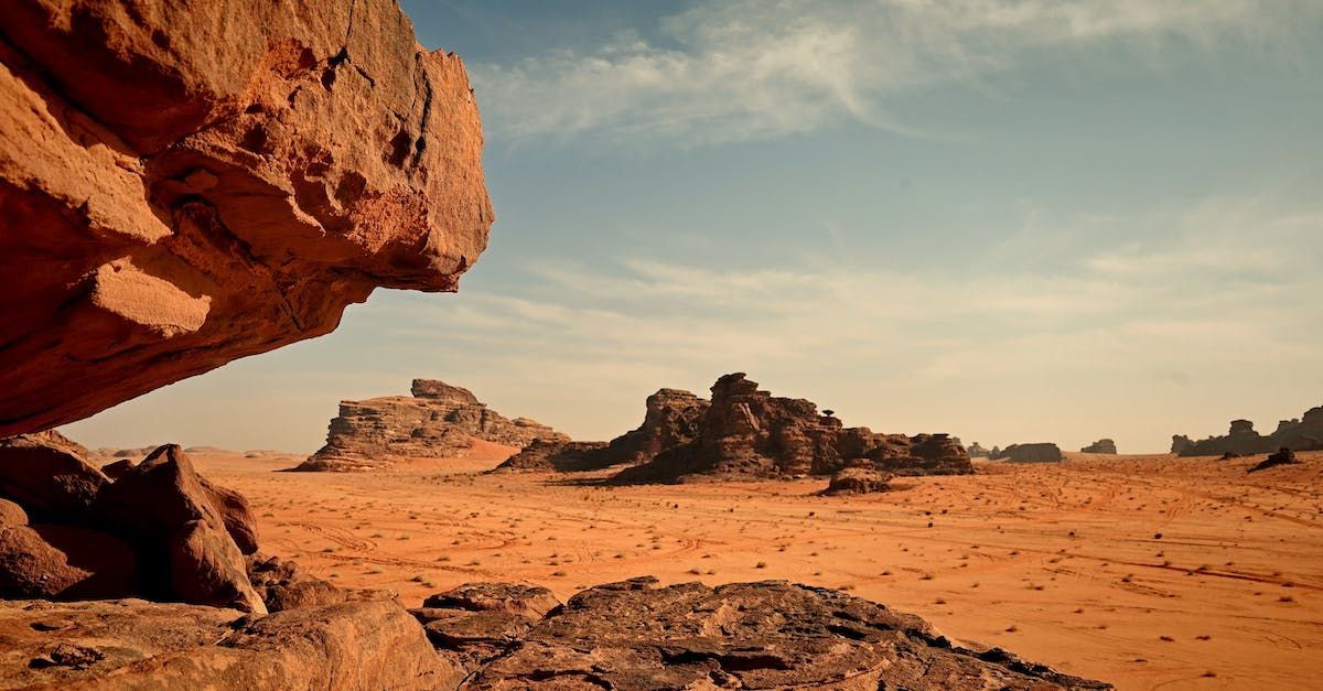 A desert landscape with rocks in the foreground and a blue sky in the background.