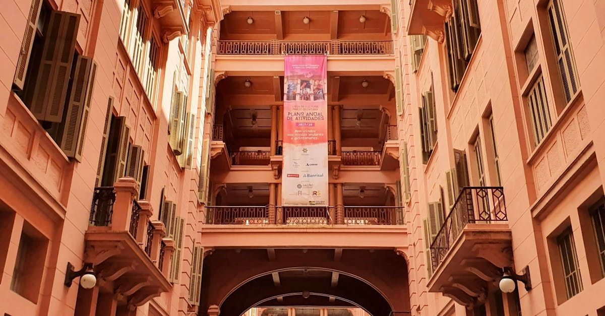 Arched courtyard with balconies and a hanging banner in warm terracotta tones