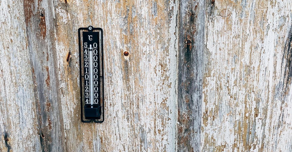 A thermometer is hanging on a rusty metal wall.