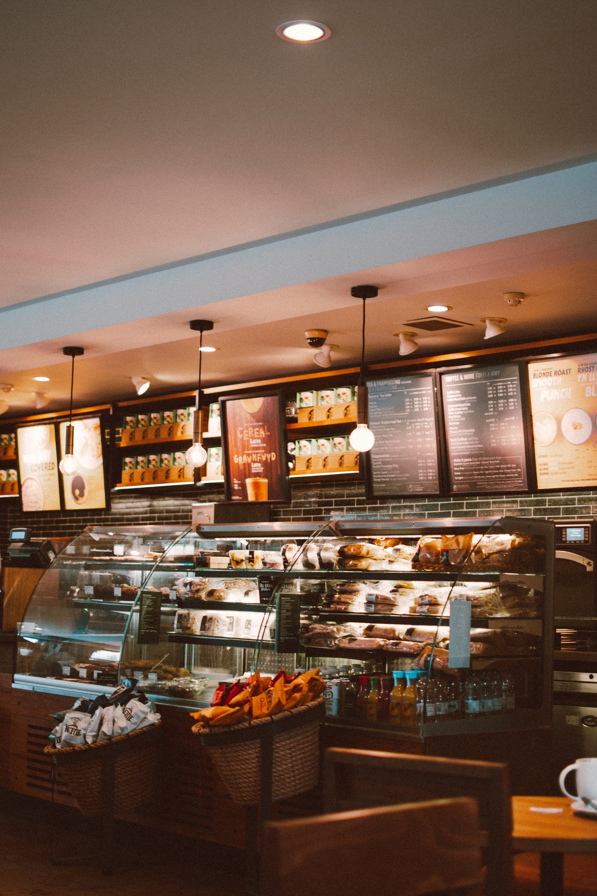 A coffee shop with a display case filled with lots of food and drinks.