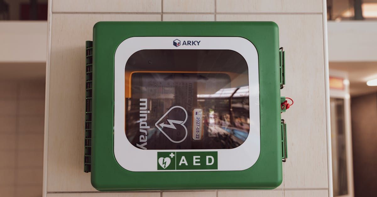 Green AED box on a wall, with visible contents inside and the words 
