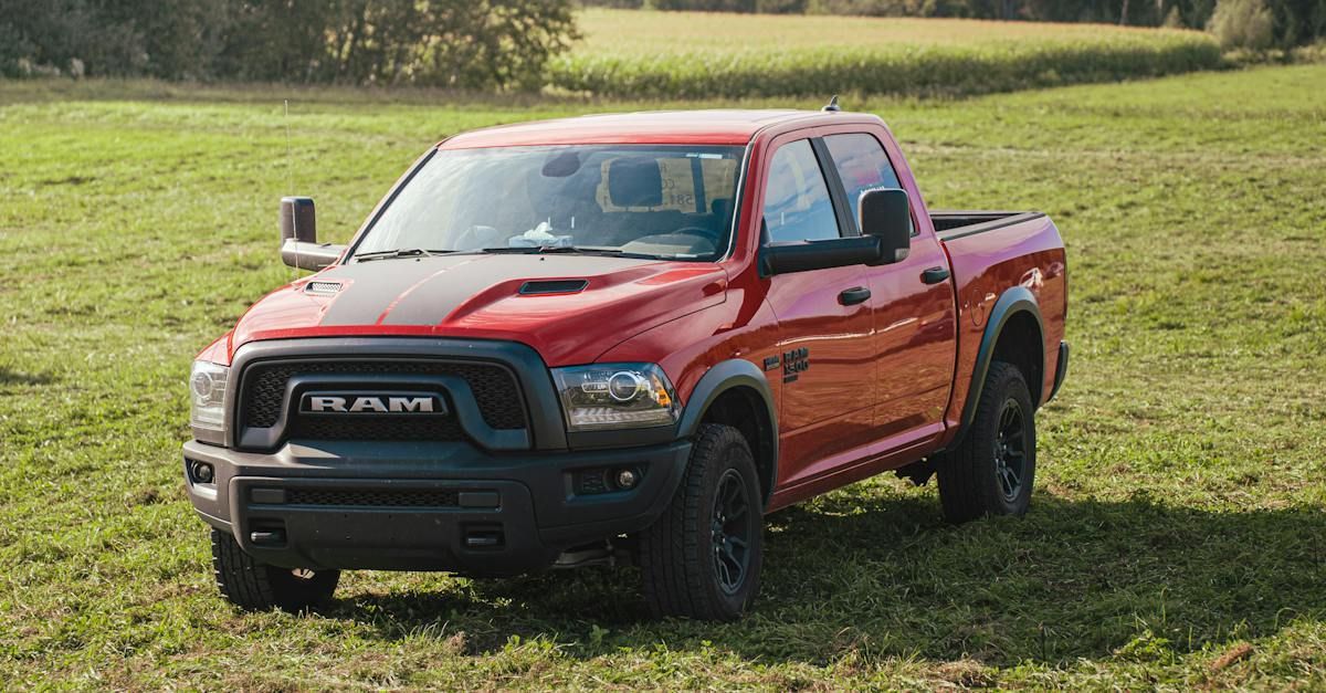 A red dodge ram truck is parked in a grassy field.