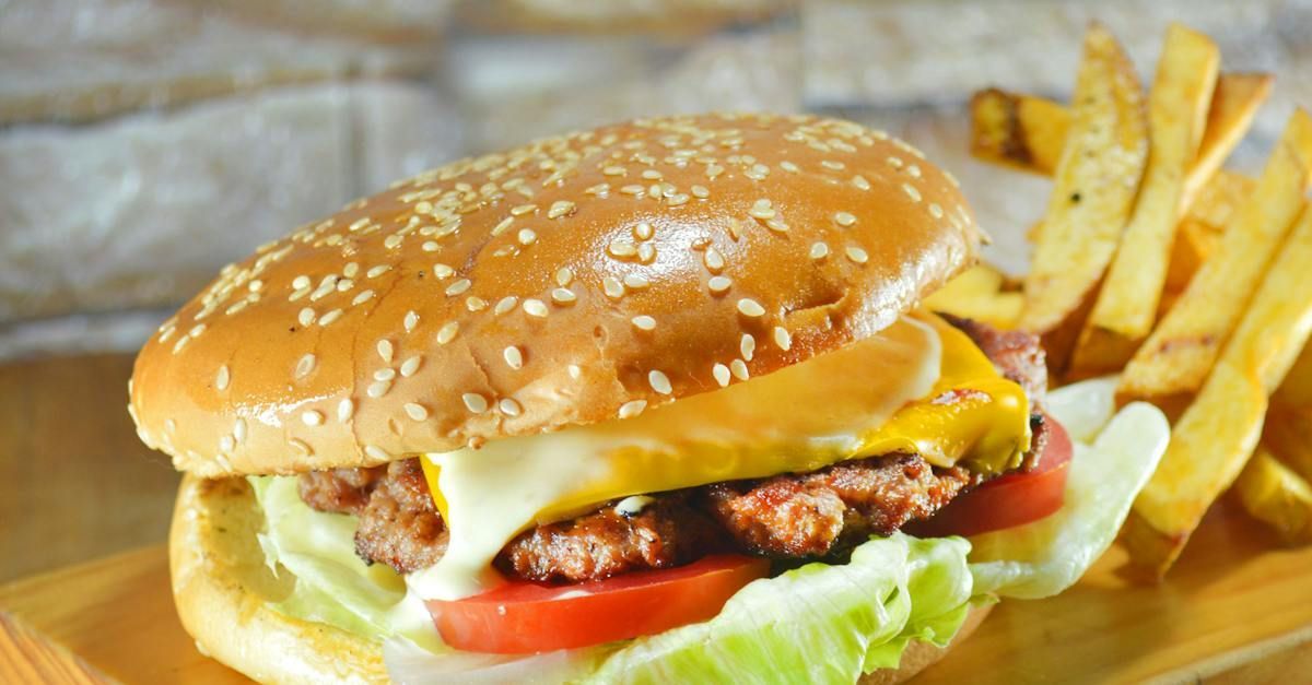 A hamburger and french fries are on a wooden cutting board.