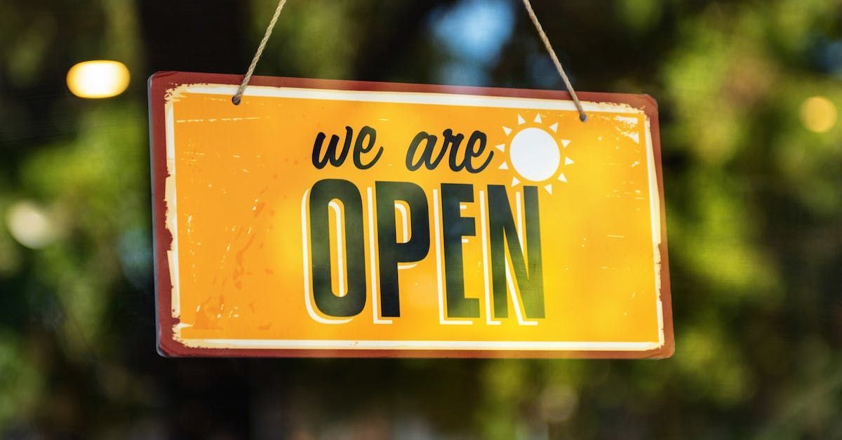 A yellow sign that says `` we are open '' is hanging from a string.