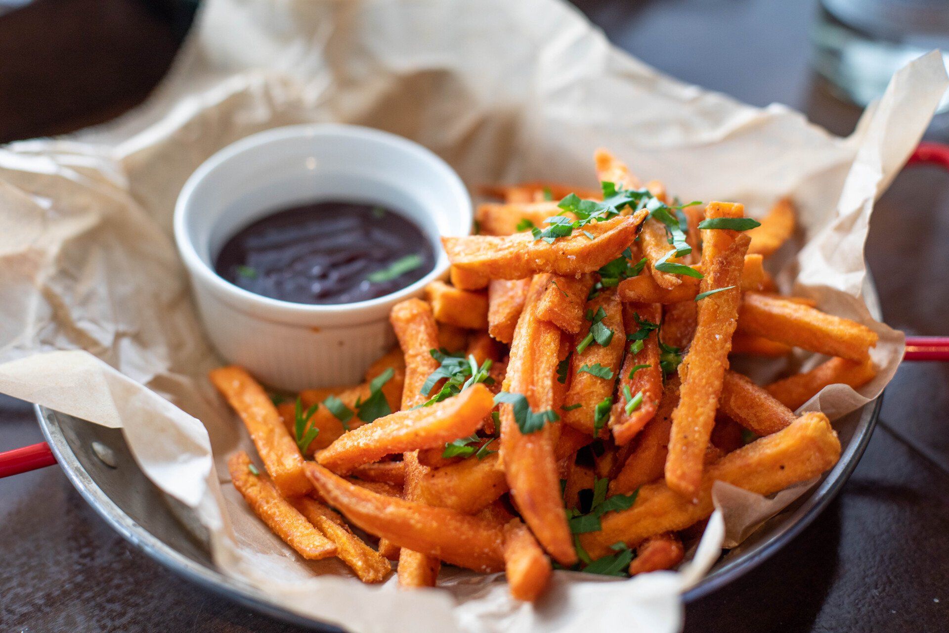 A plate of french fries with a bowl of dipping sauce on a table.