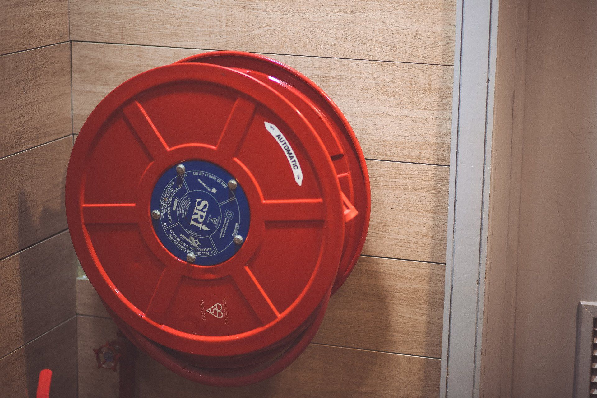 A red fire hose reel is hanging on a wall.