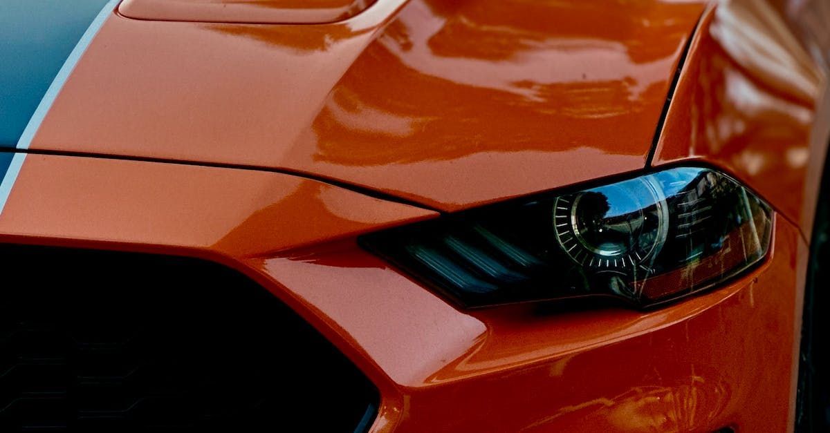 A close up of the headlight of an orange mustang.