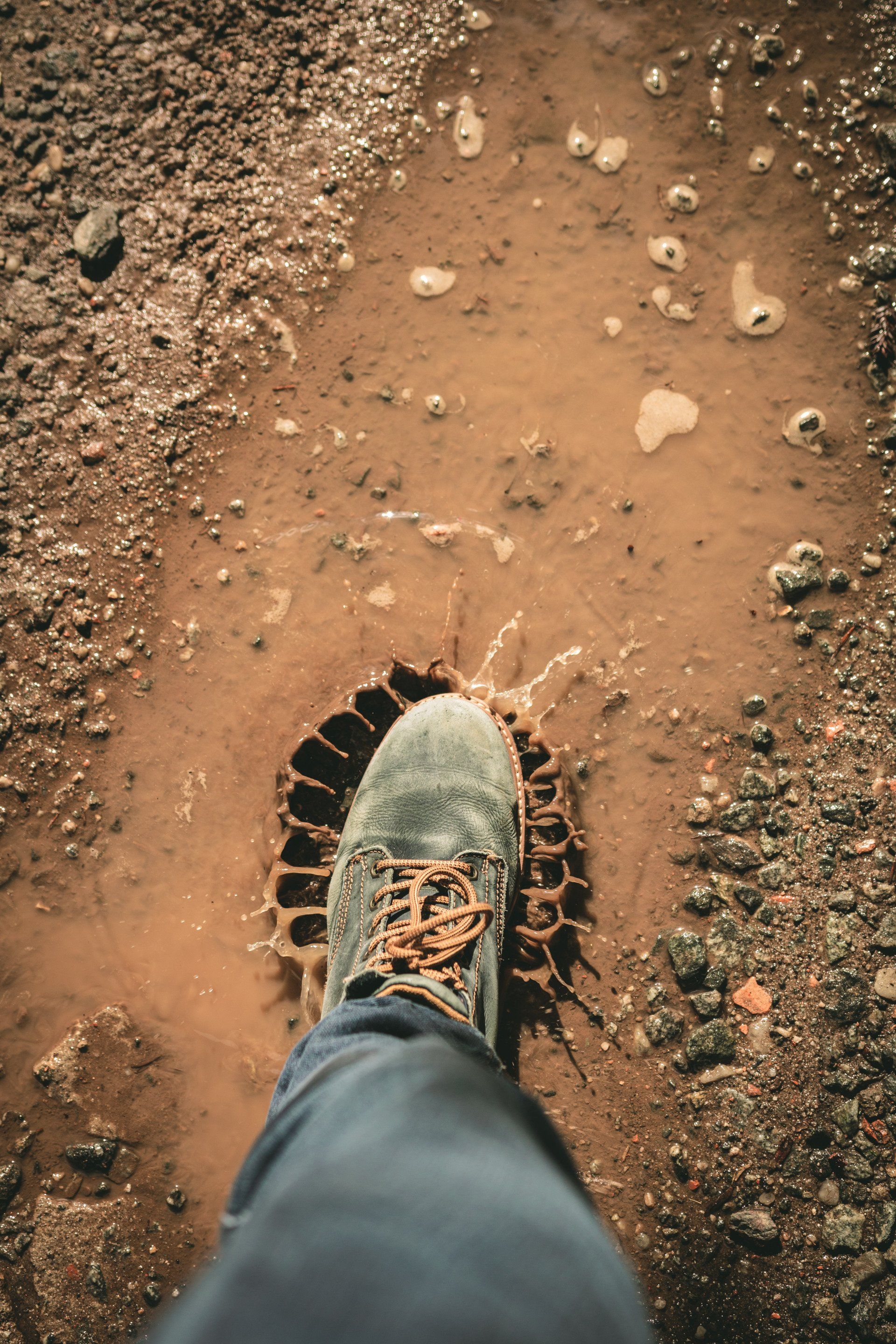 A person's foot is standing in a muddy puddle.