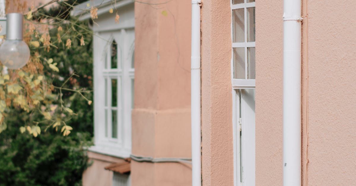 A close up of a pink house with a white door and window.