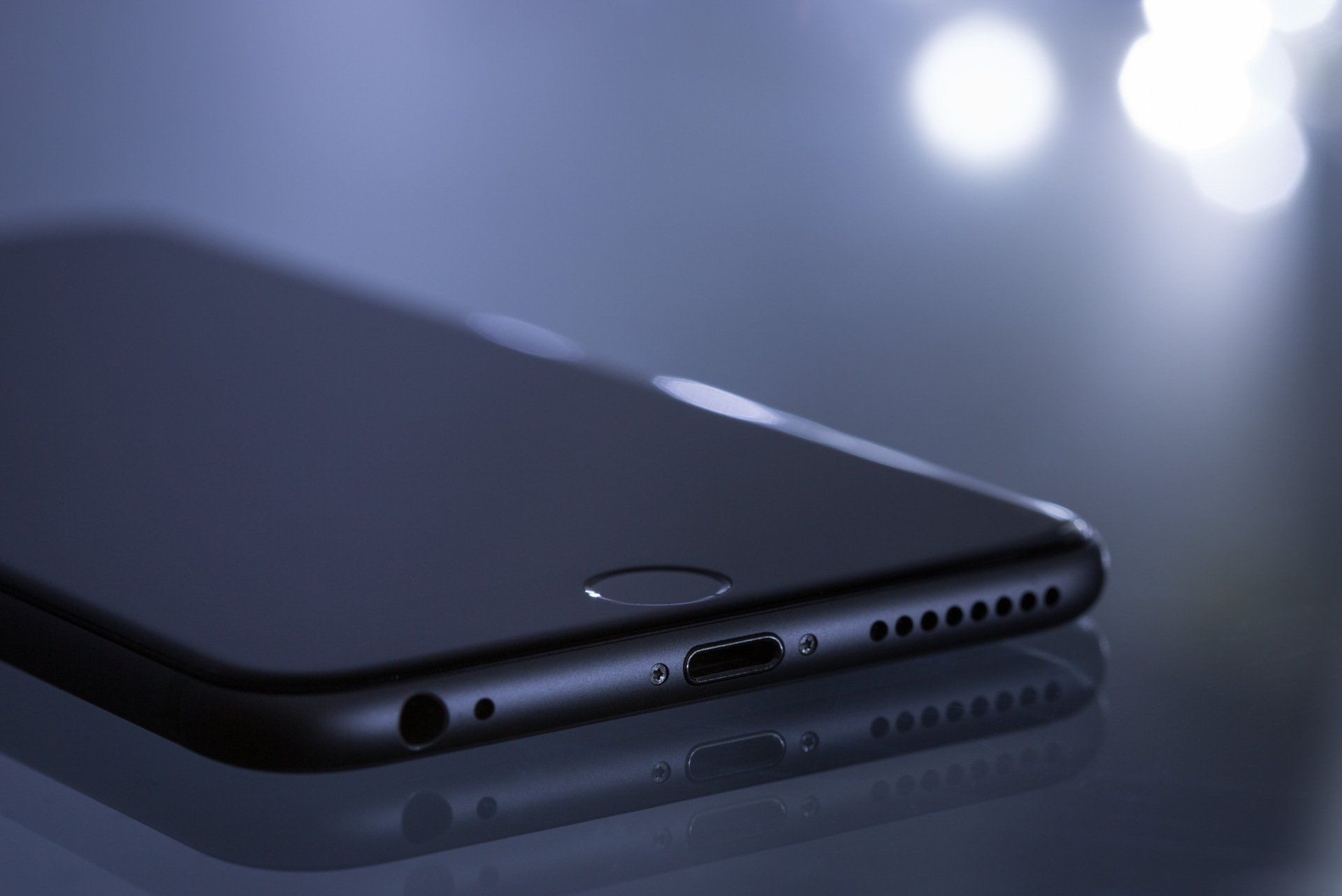 A close up of the bottom of a cell phone on a table.