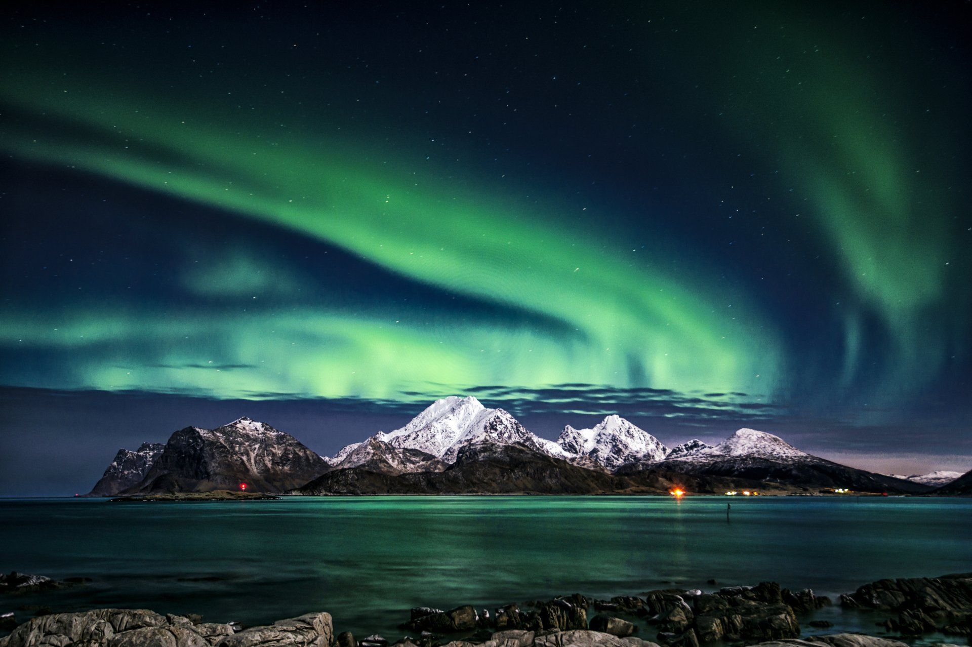 Nordlyset skinner over fjellene og havet.
