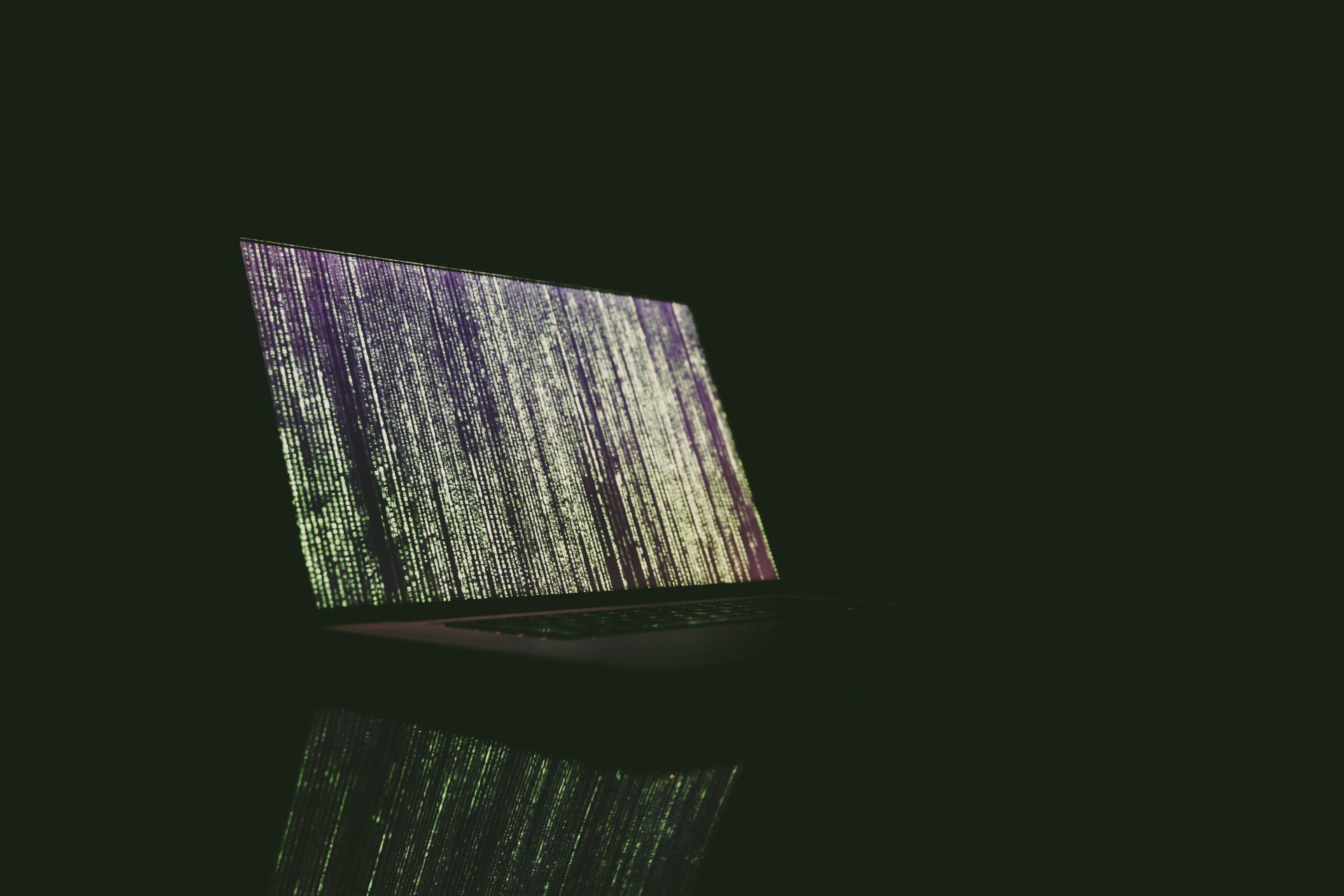 A laptop computer is sitting on a table in the dark.