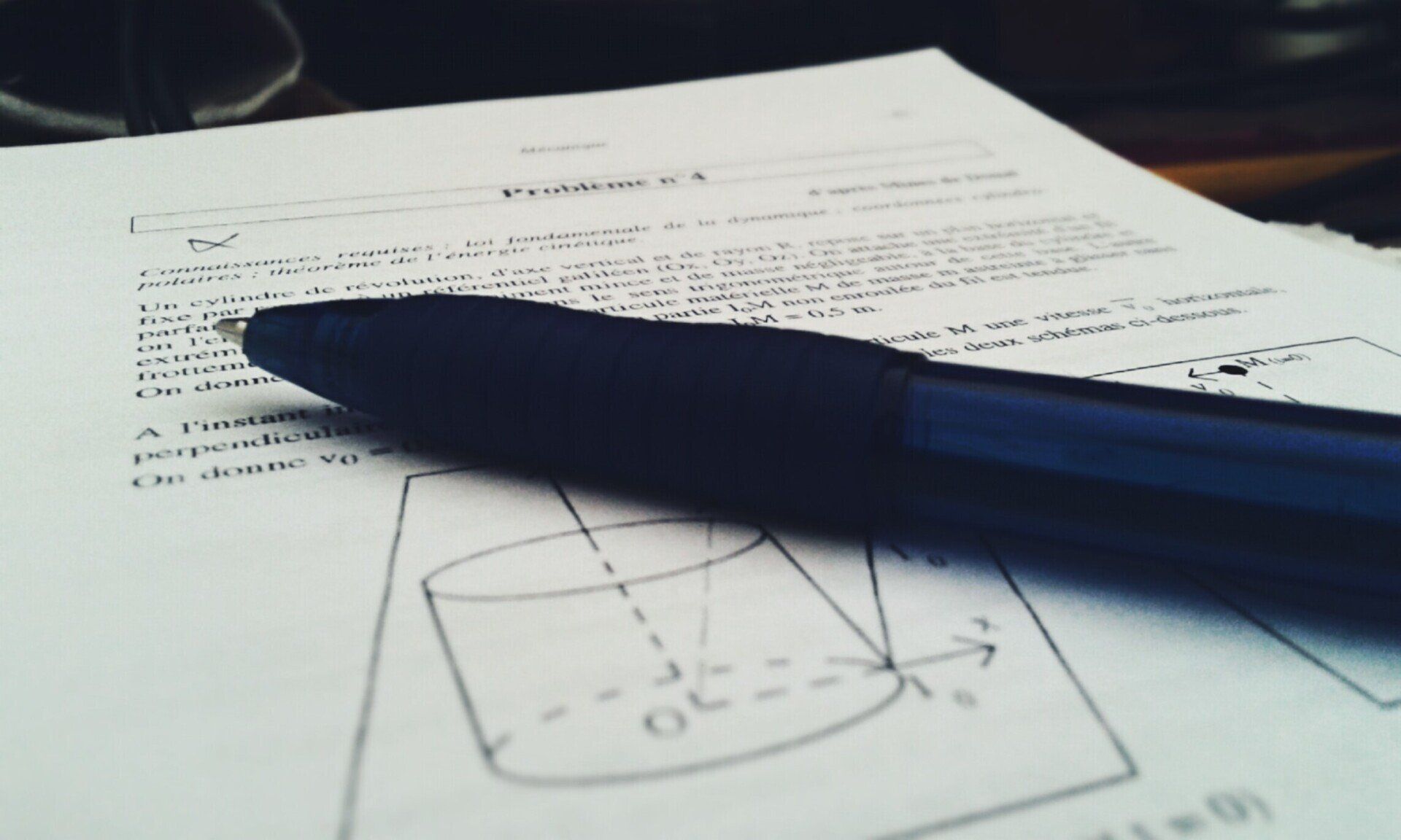 A pen rests on a piece of paper with a drawing of a cone on it