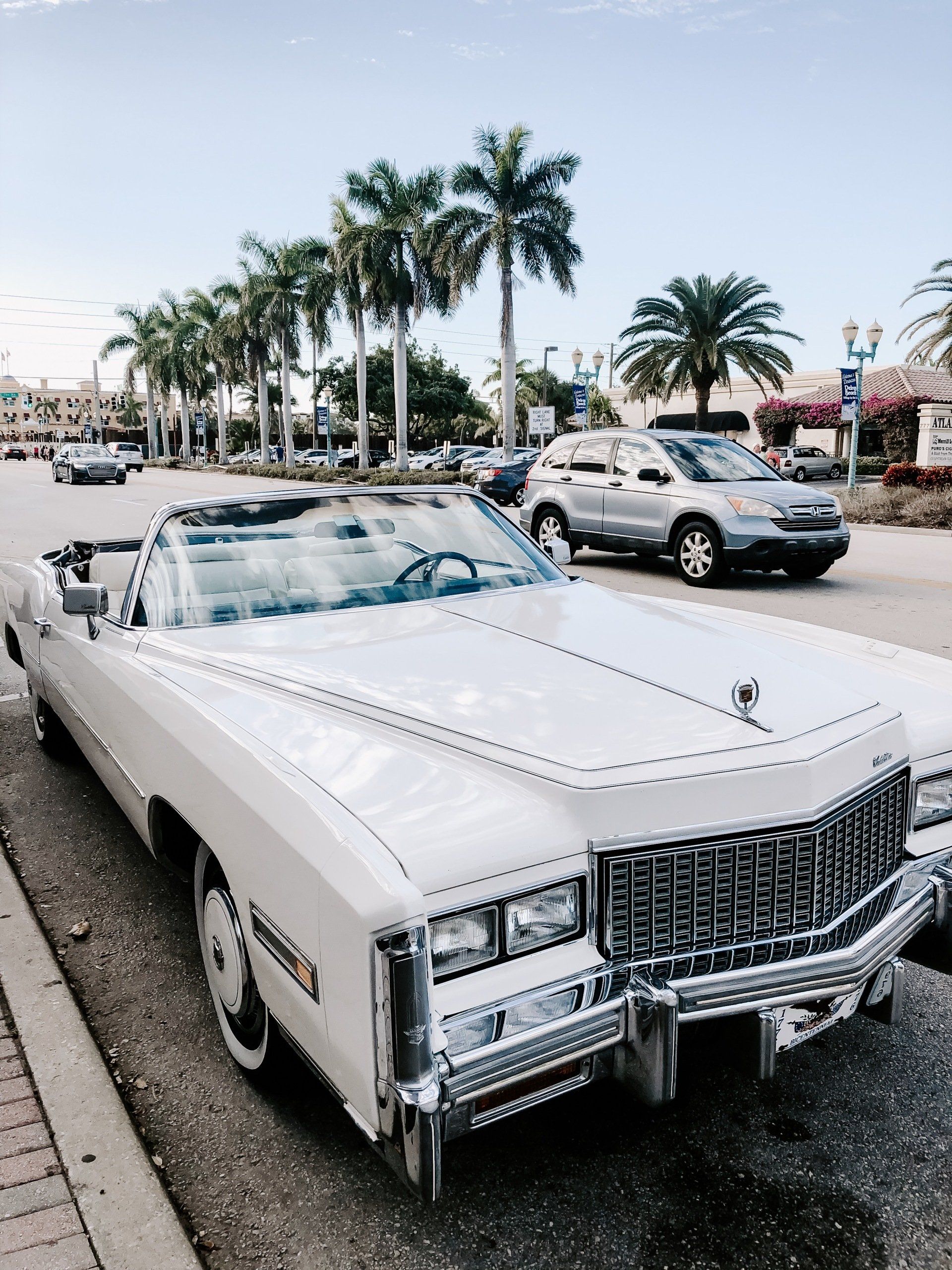 A white cadillac is parked on the side of the road.