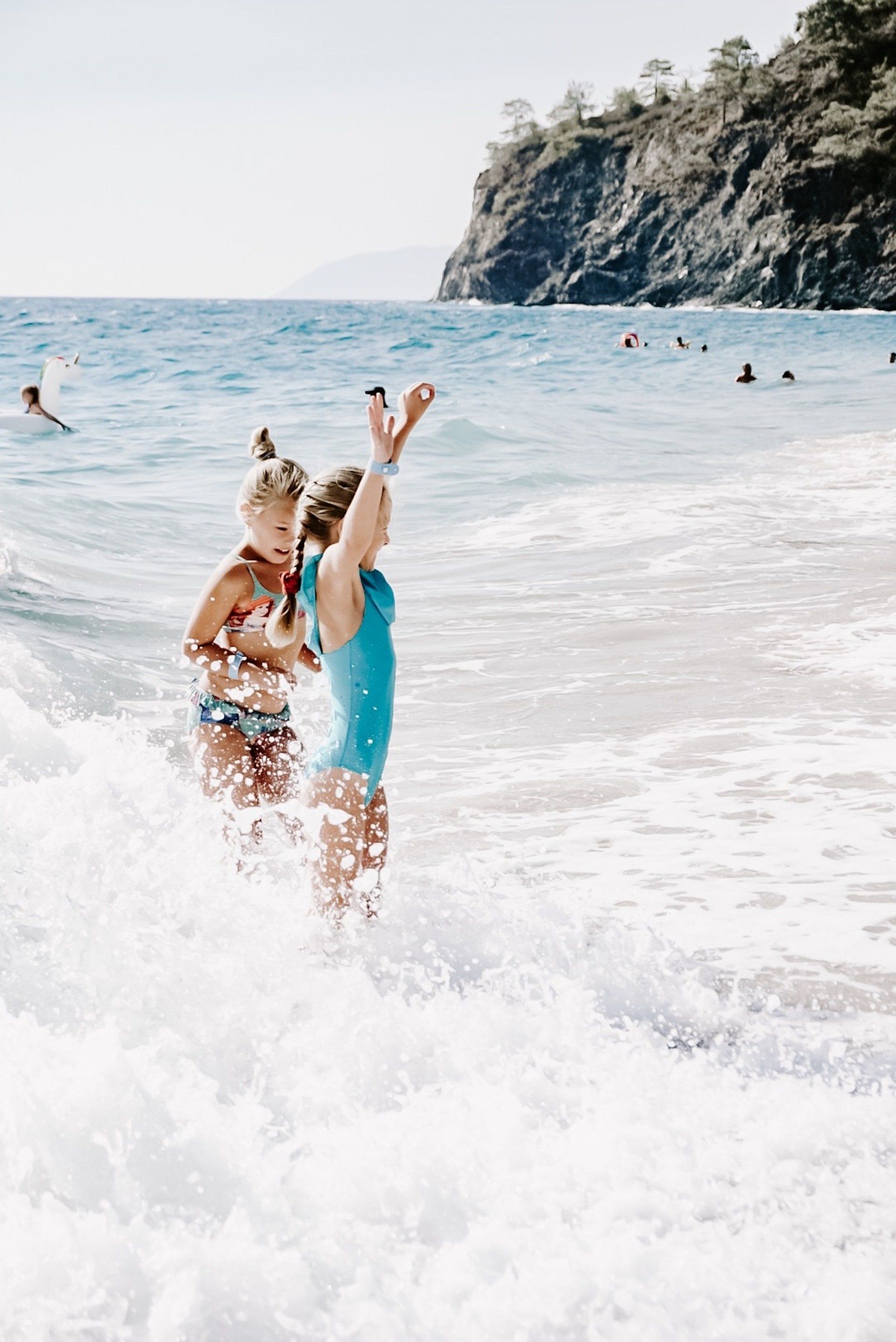 Two women are playing in the ocean on a beach.