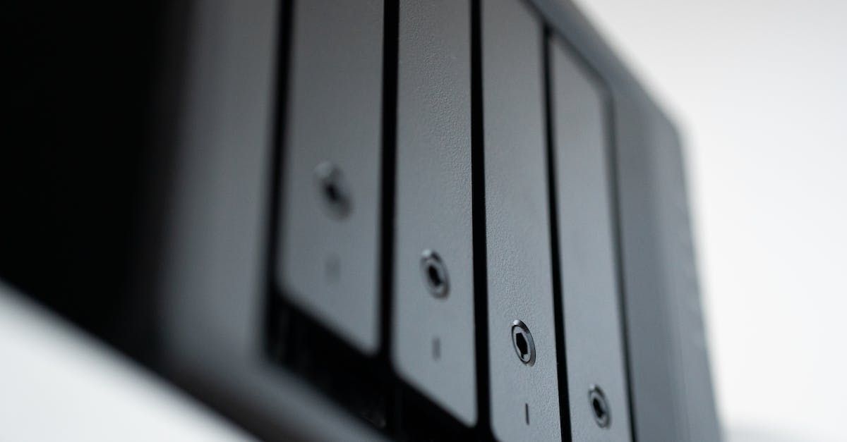 Close-up van een zwart apparaat met verticale gleuven en kleine ronde gaten, mogelijk een computer of opslagmedium.