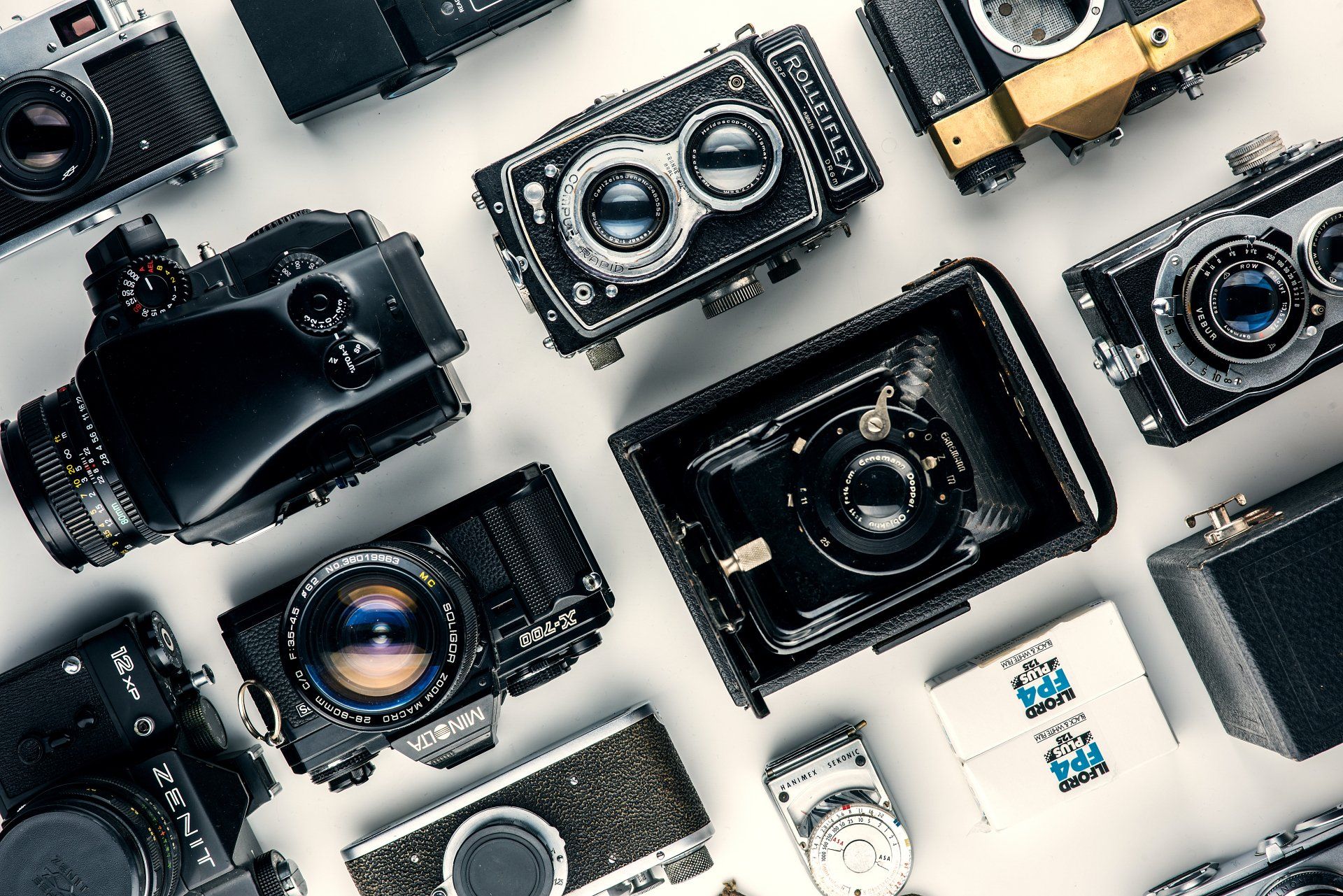 Diverse digitale camera's en lenzen opgesteld op een lichte achtergrond.