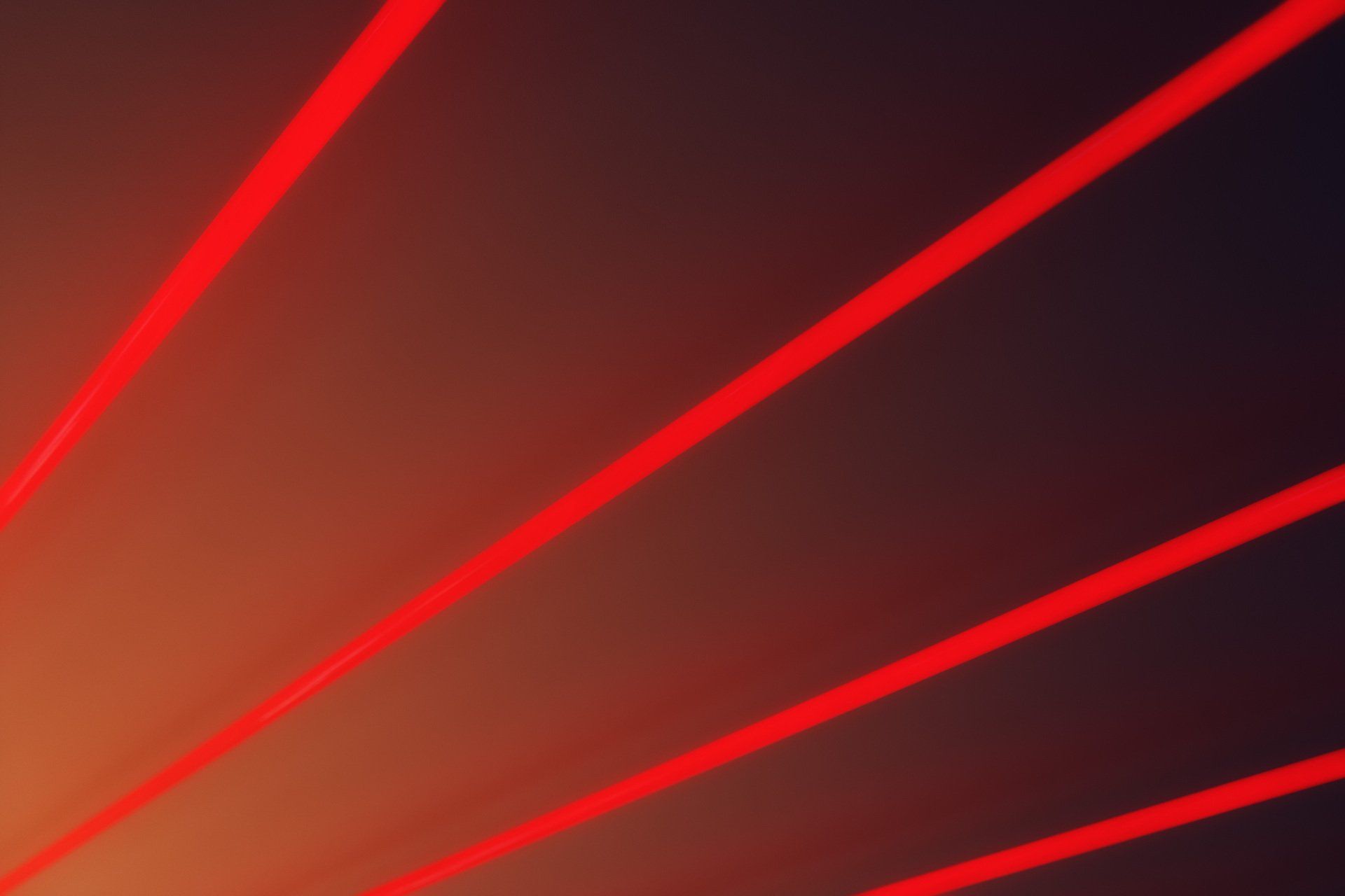 A close up of a red laser beam on a dark background.