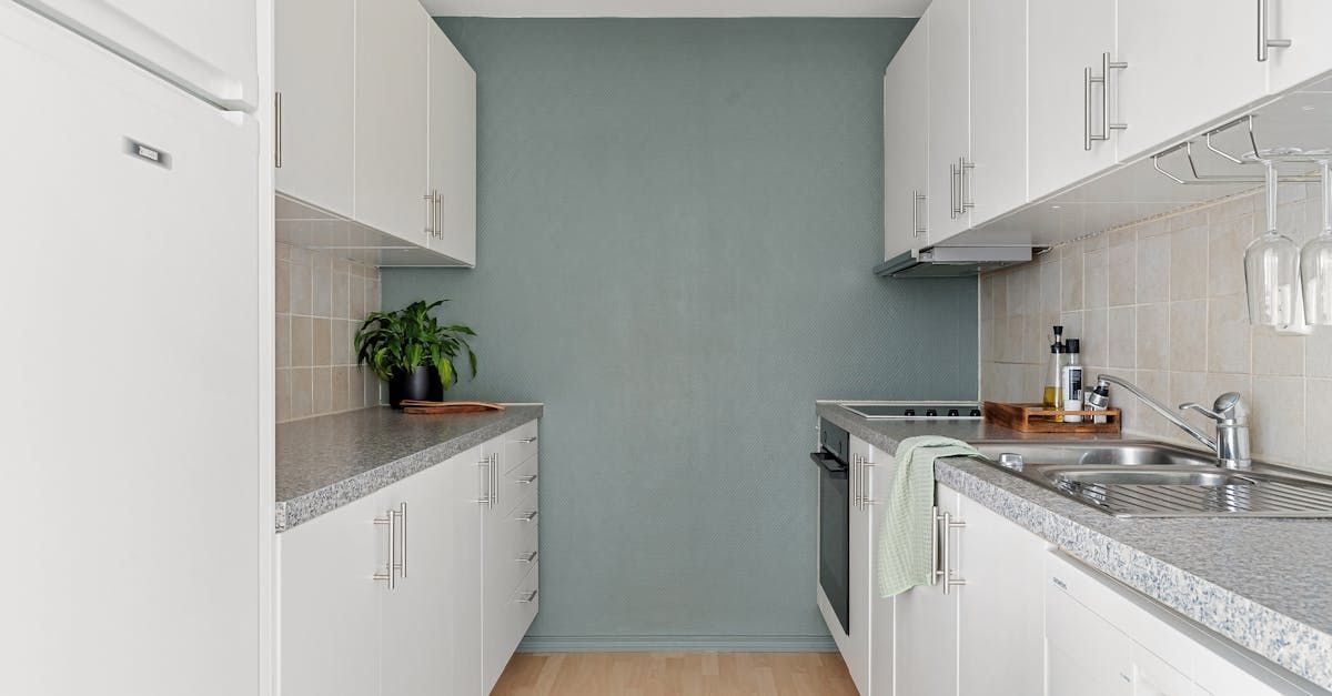 A kitchen with white cabinets and a blue wall.
