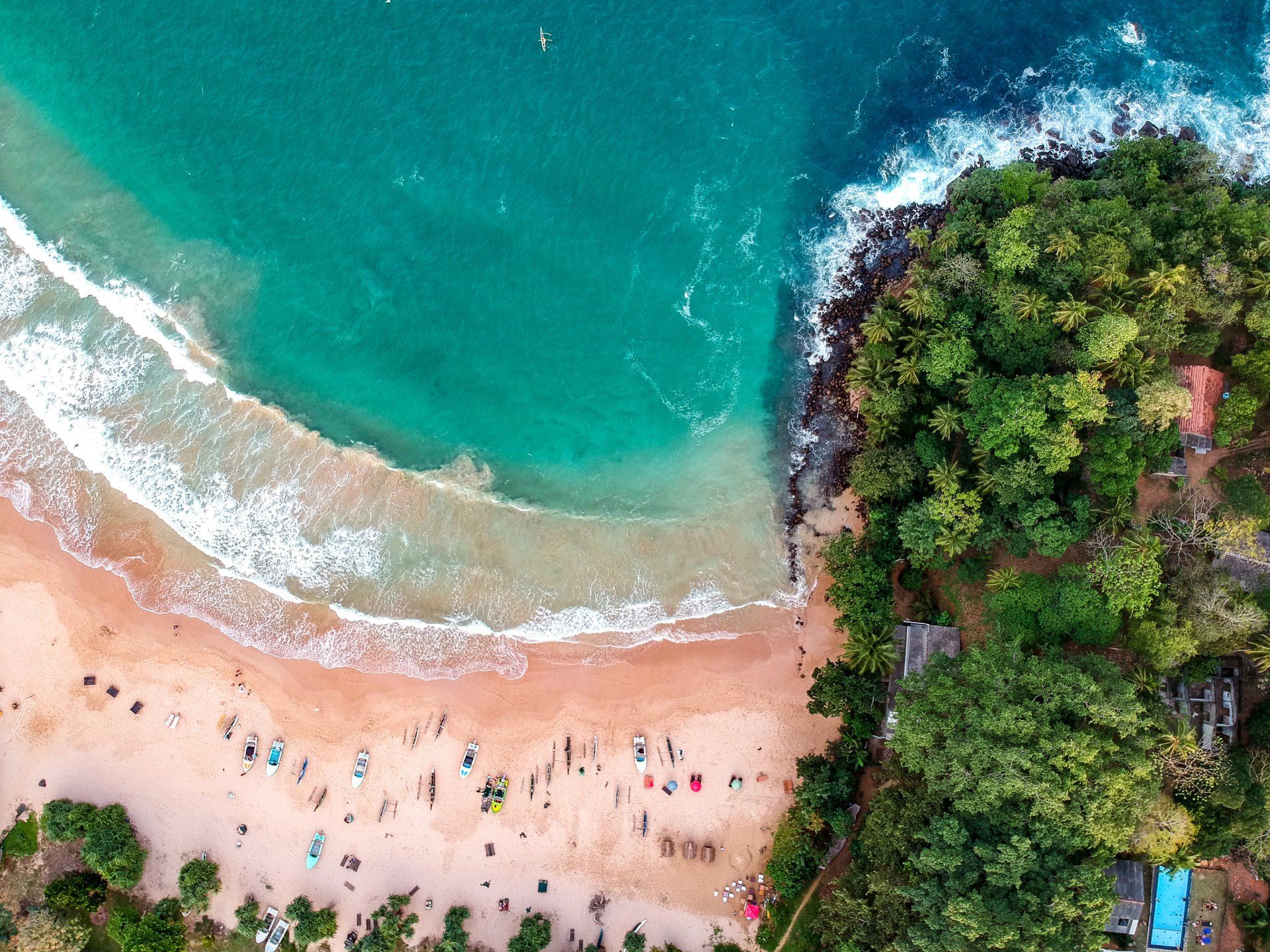 An aerial view of a beach surrounded by trees and a body of water.