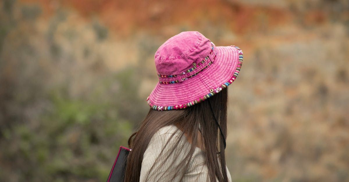 A woman wearing a pink hat and a backpack is walking.
