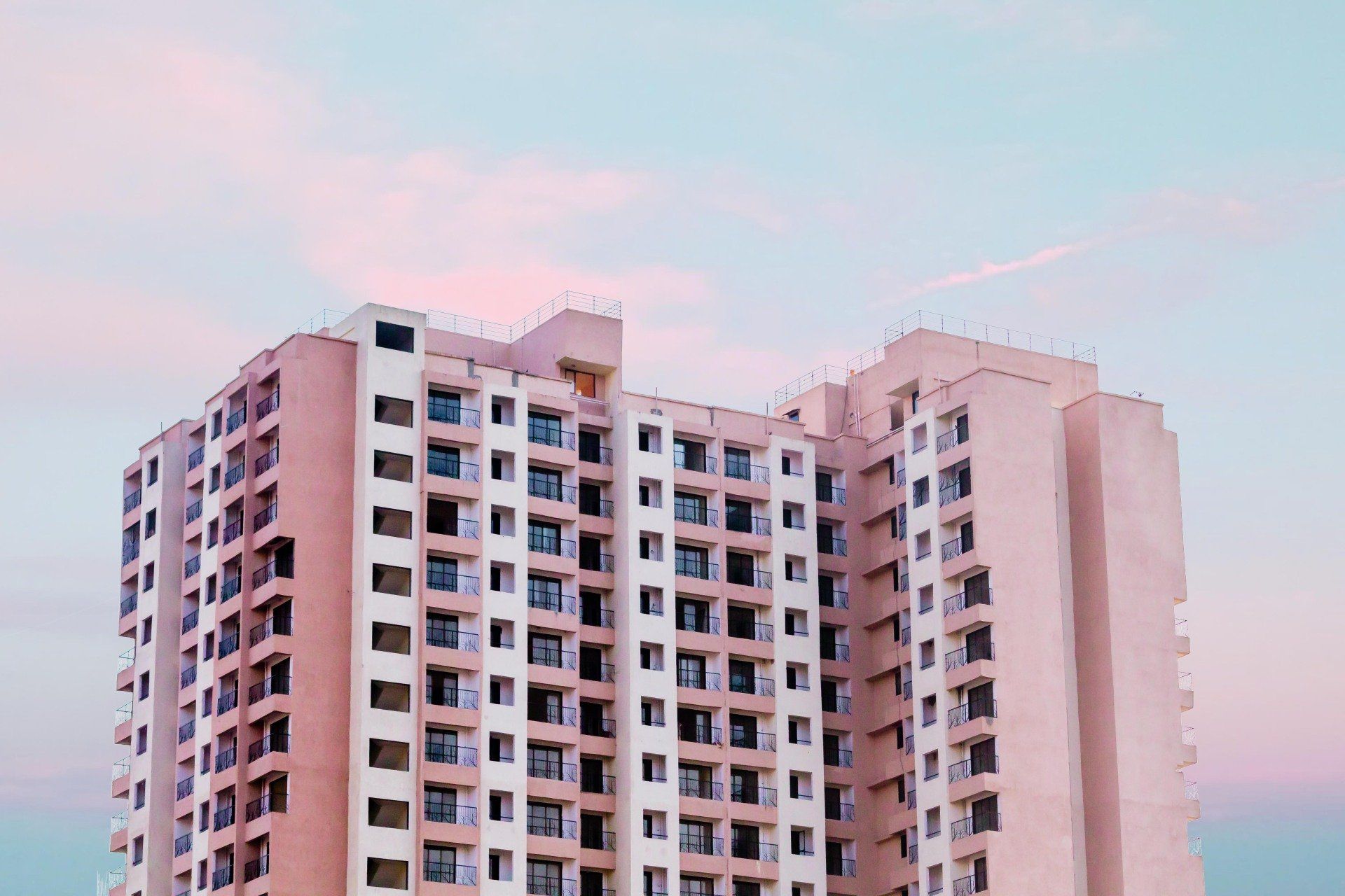 A tall building with a lot of windows is against a blue sky.