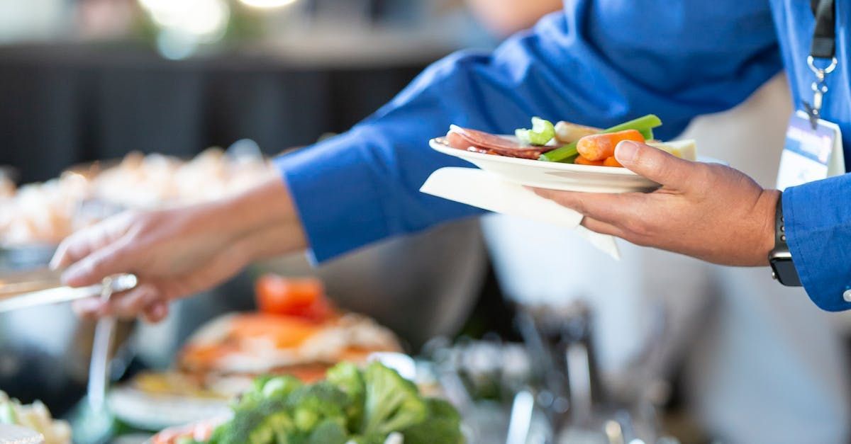 A person is taking a plate of food from a buffet.