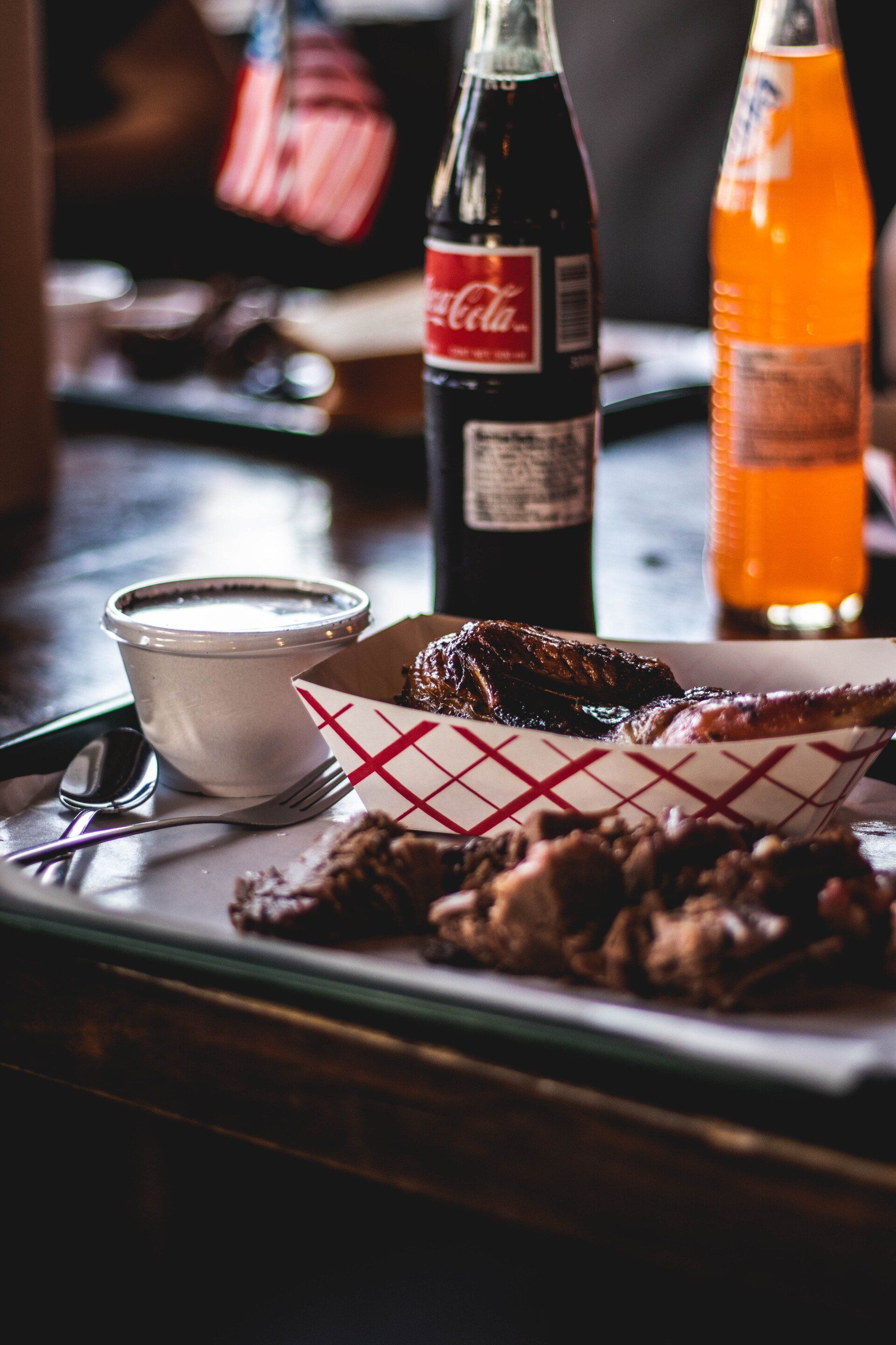 A tray of food and a bottle of coca cola on a table.