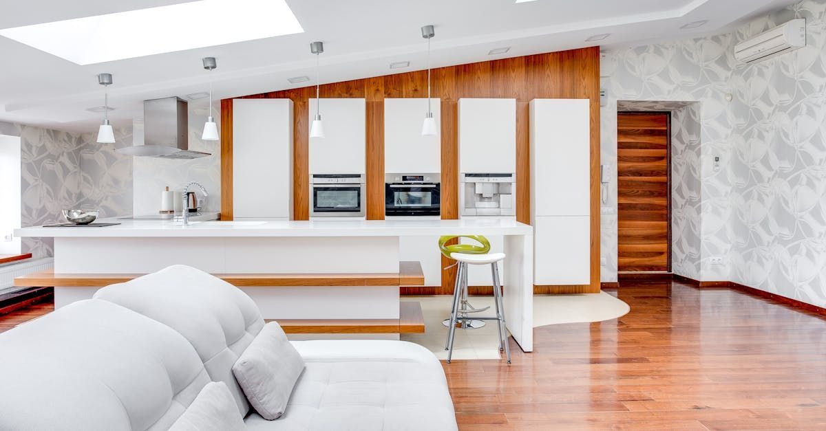 Bright modern open-plan living room and kitchen with white sofa, wood floors, and bar seating