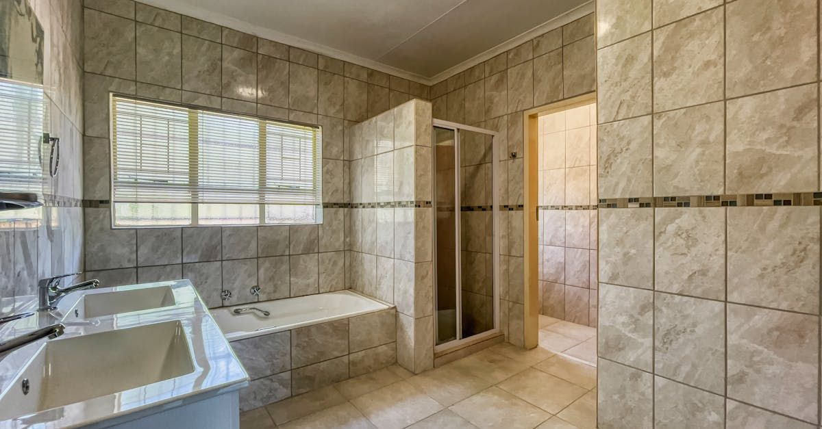 A bathroom with a sink , tub , shower and mirror.