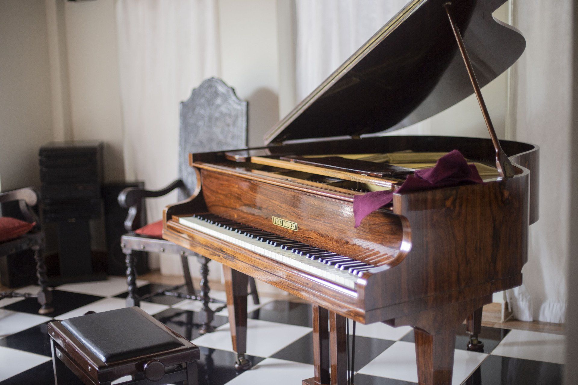 Un pianoforte a coda è seduto in una stanza con il pavimento a scacchi.